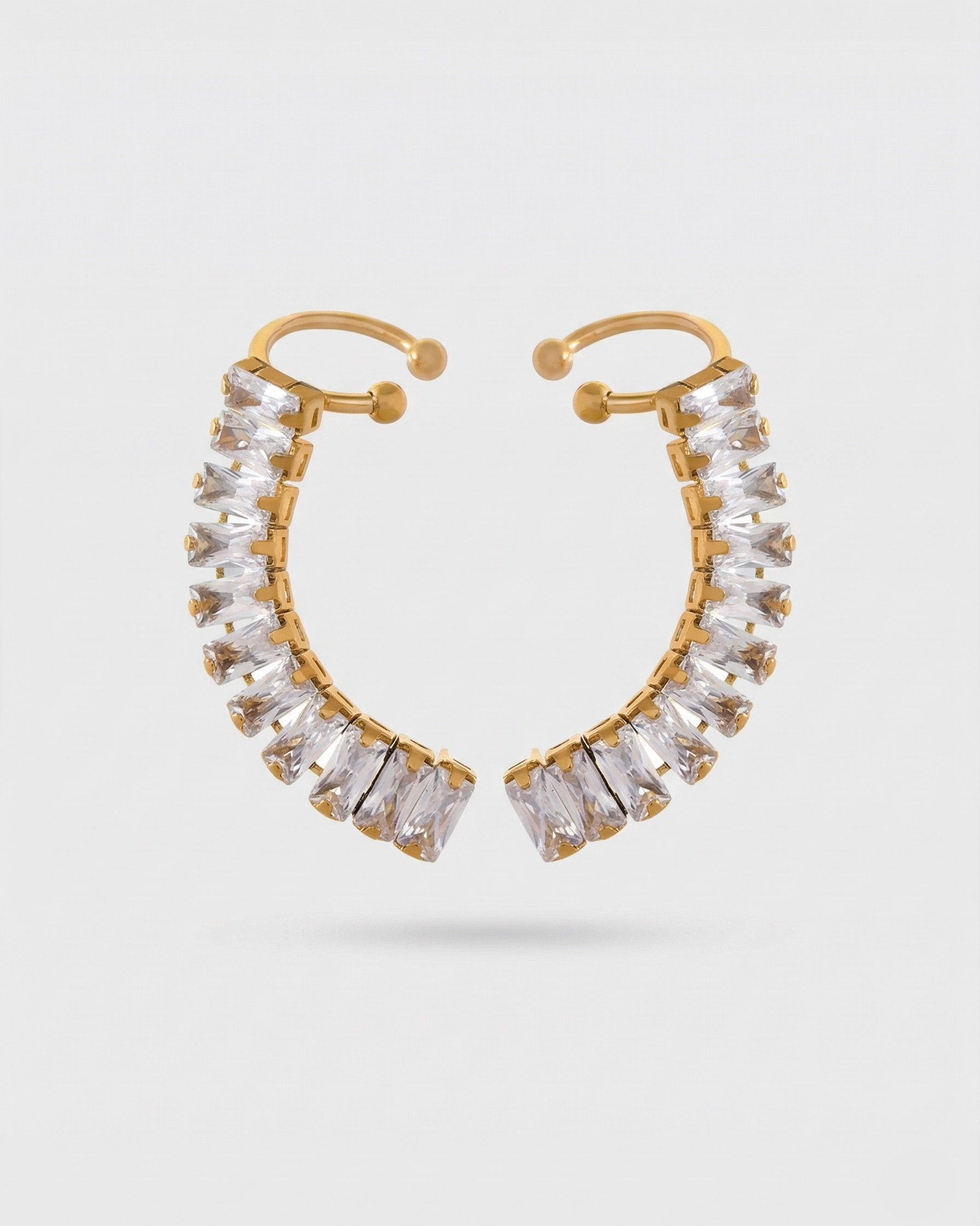 Gold hoop earrings with clear gemstones on a light gray background