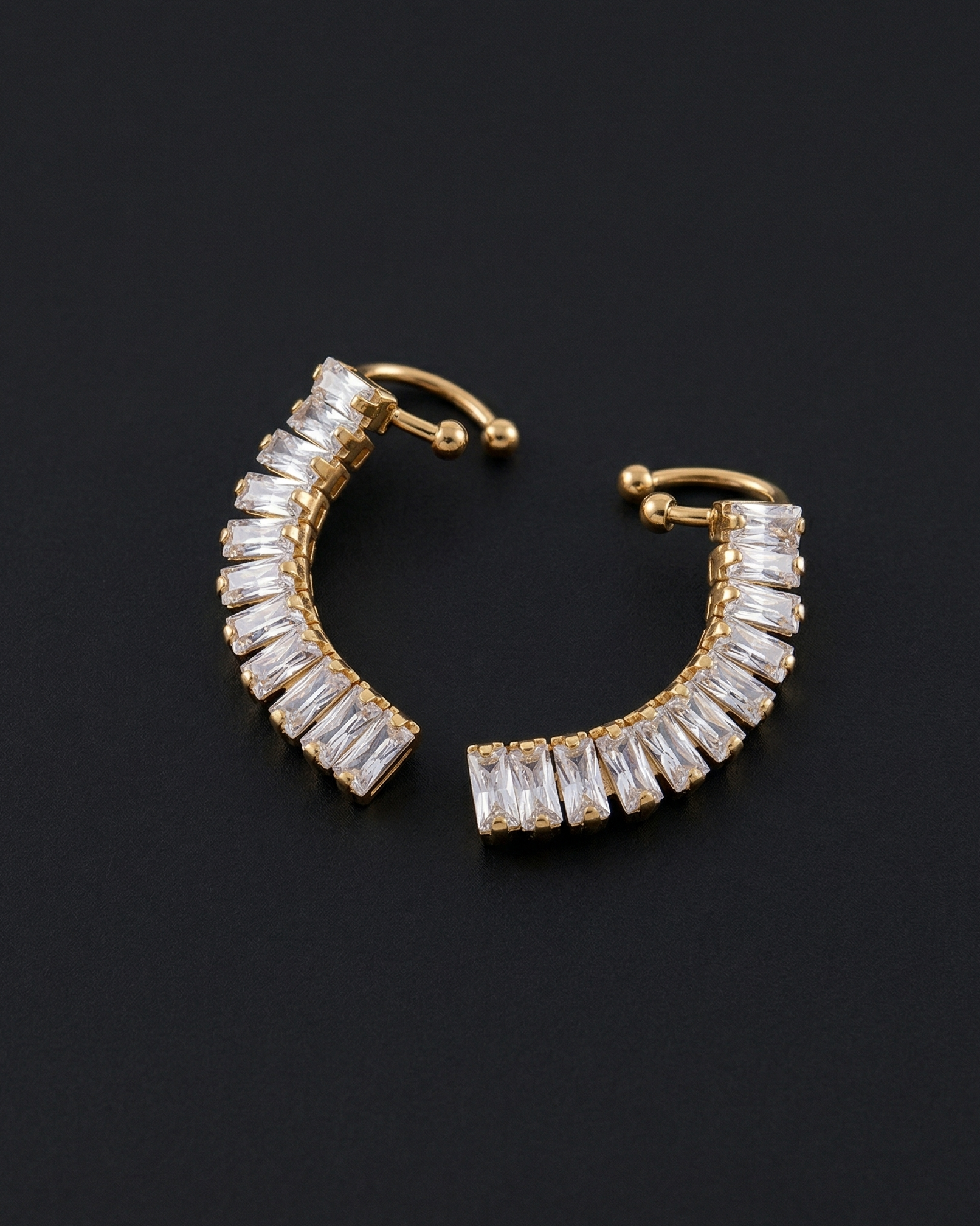 Gold hoop earrings with clear gemstones on a black background