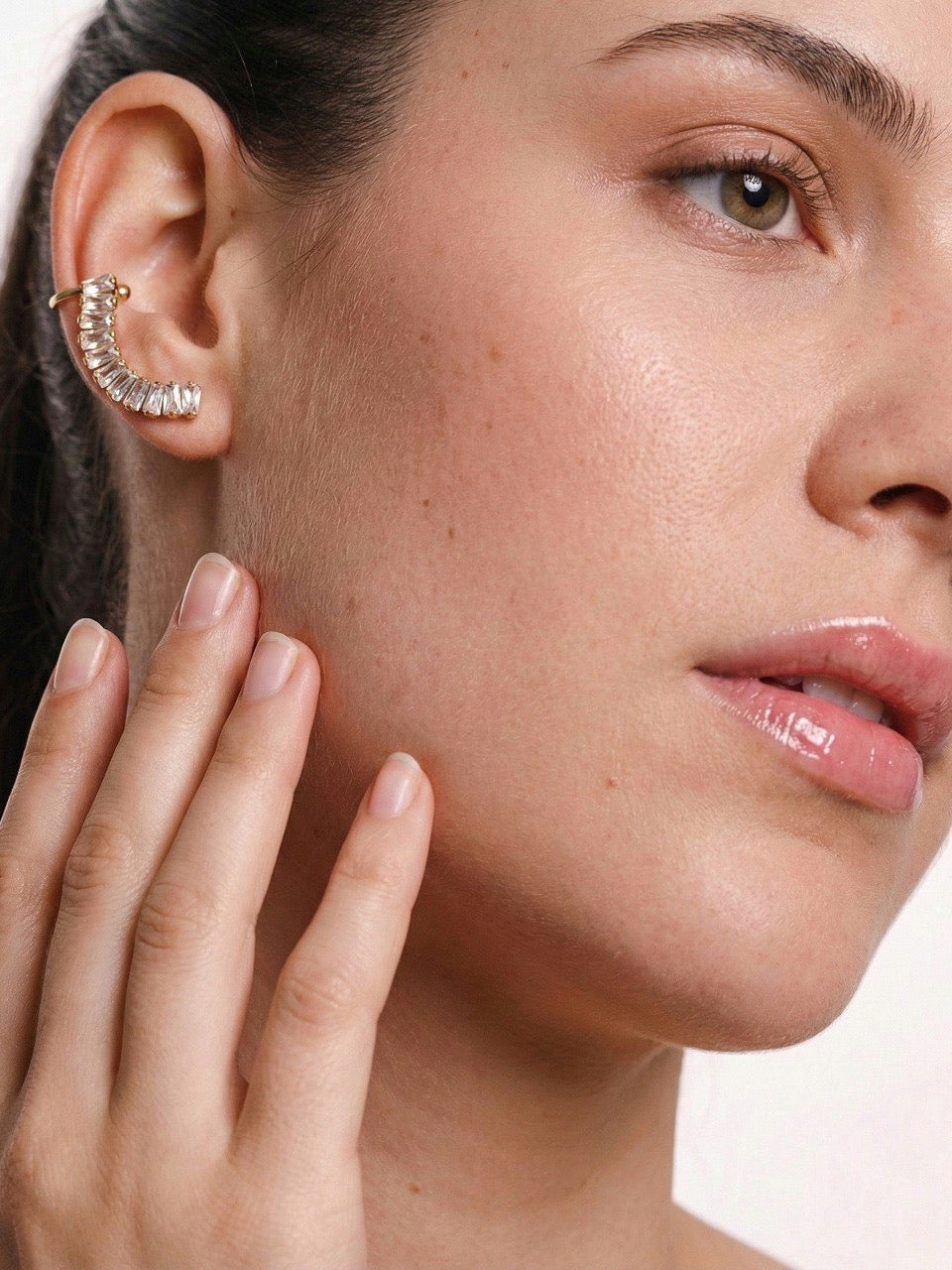 Close-up of a woman's face with a focus on her ear wearing an earring.