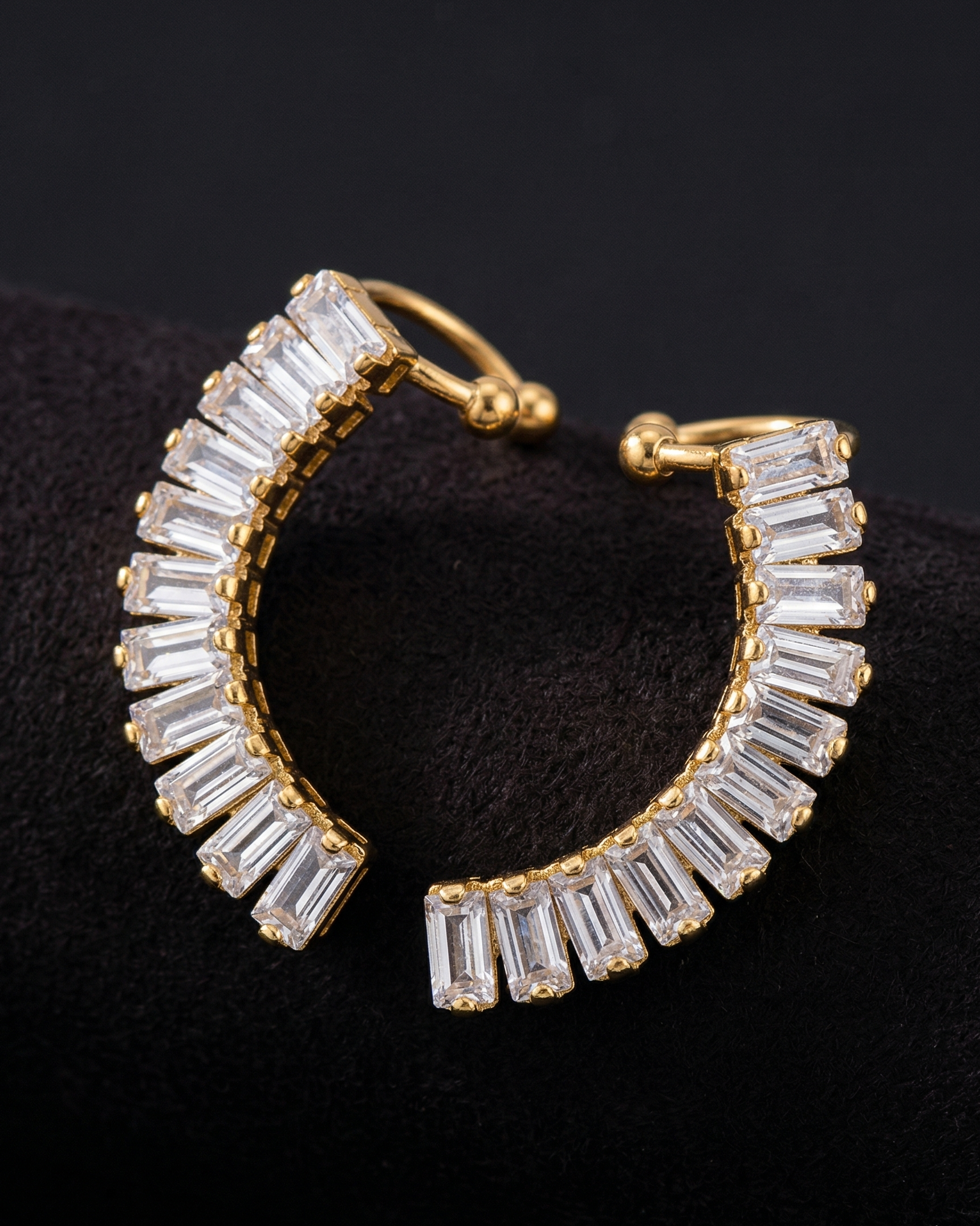 Gold hoop earrings with clear gemstones on a black background