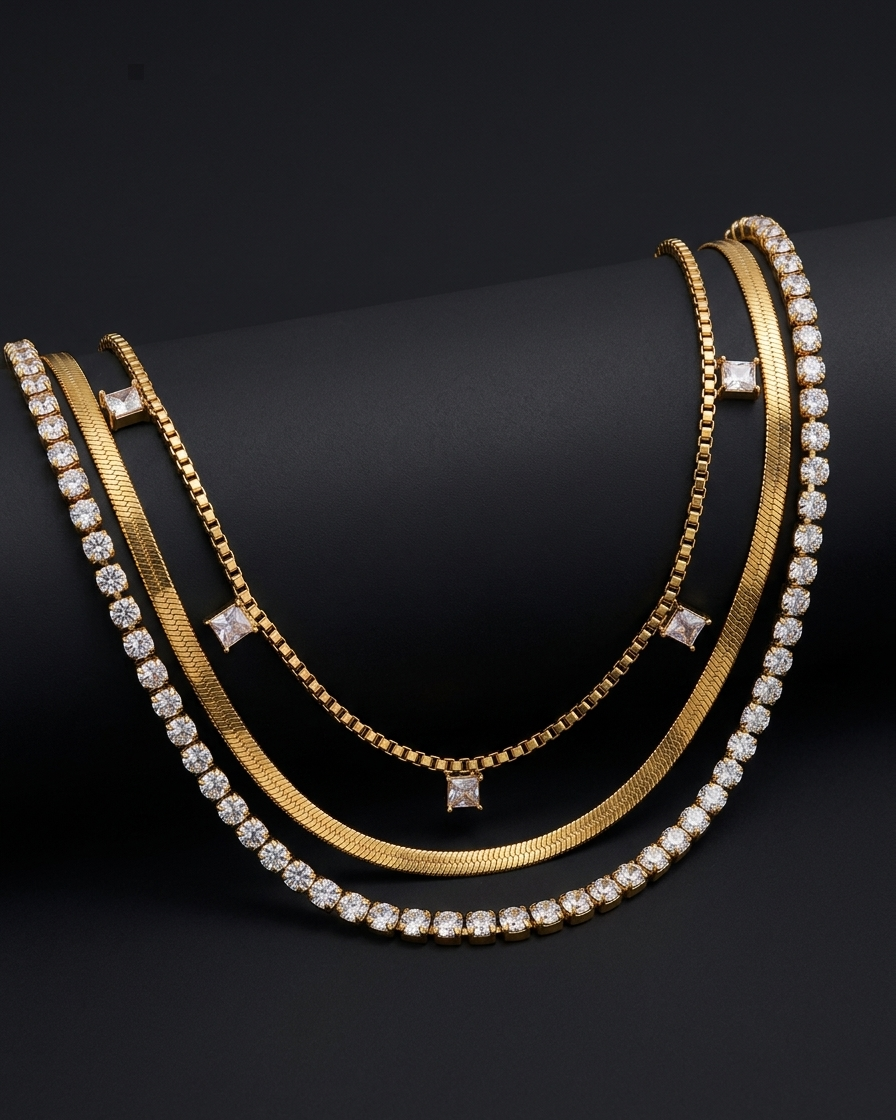 Three gold necklaces with diamond accents on a black background