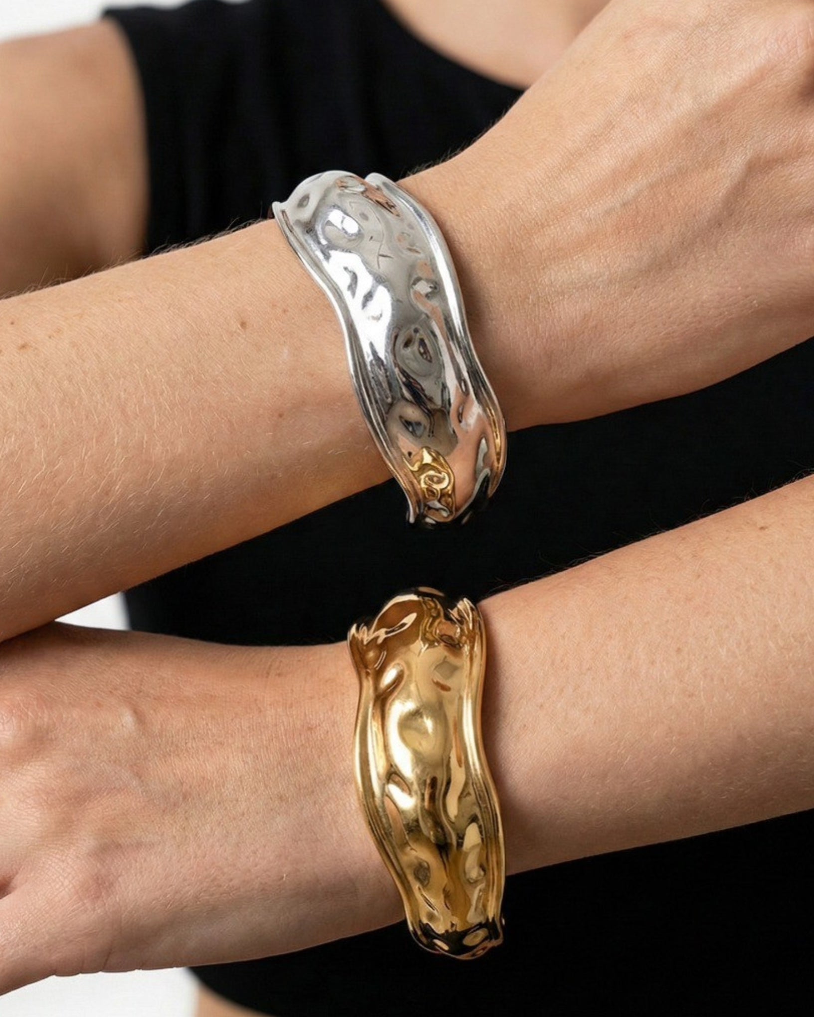 Two gold and silver bracelets on a person's wrist against a black background