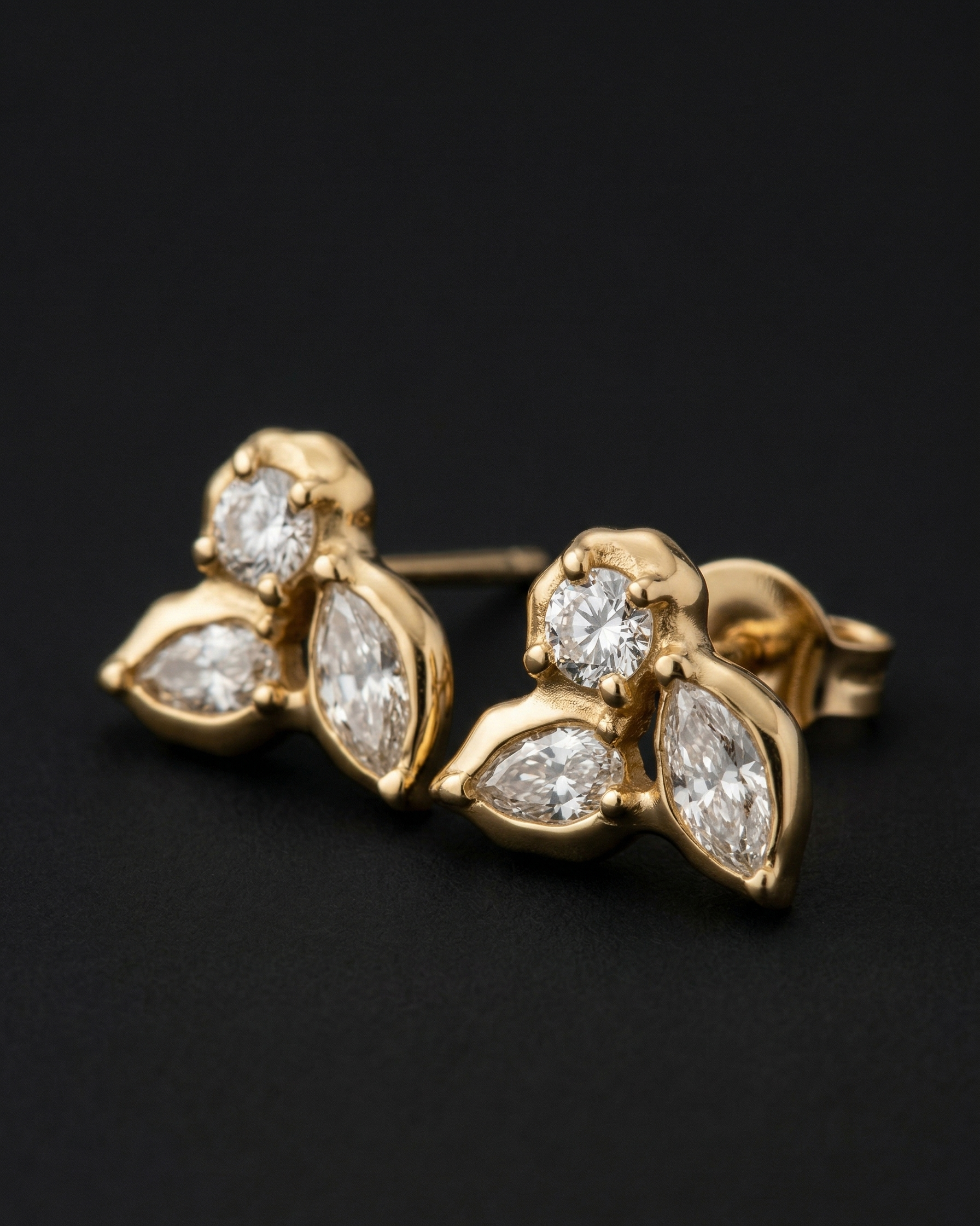 Gold earrings with diamond accents on a black background
