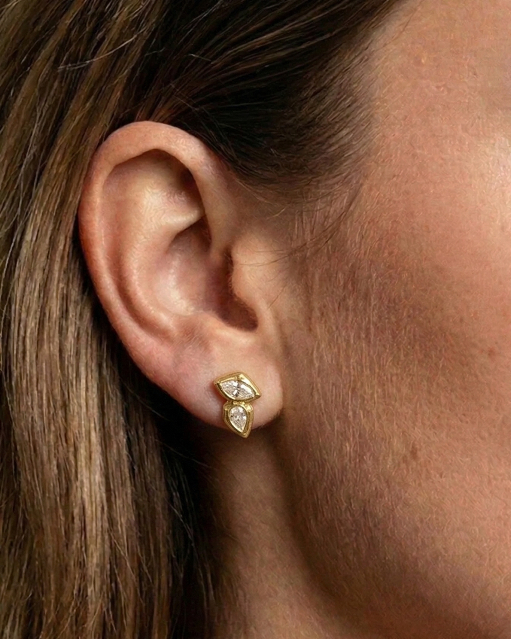 Gold earrings worn by a person with brown hair.