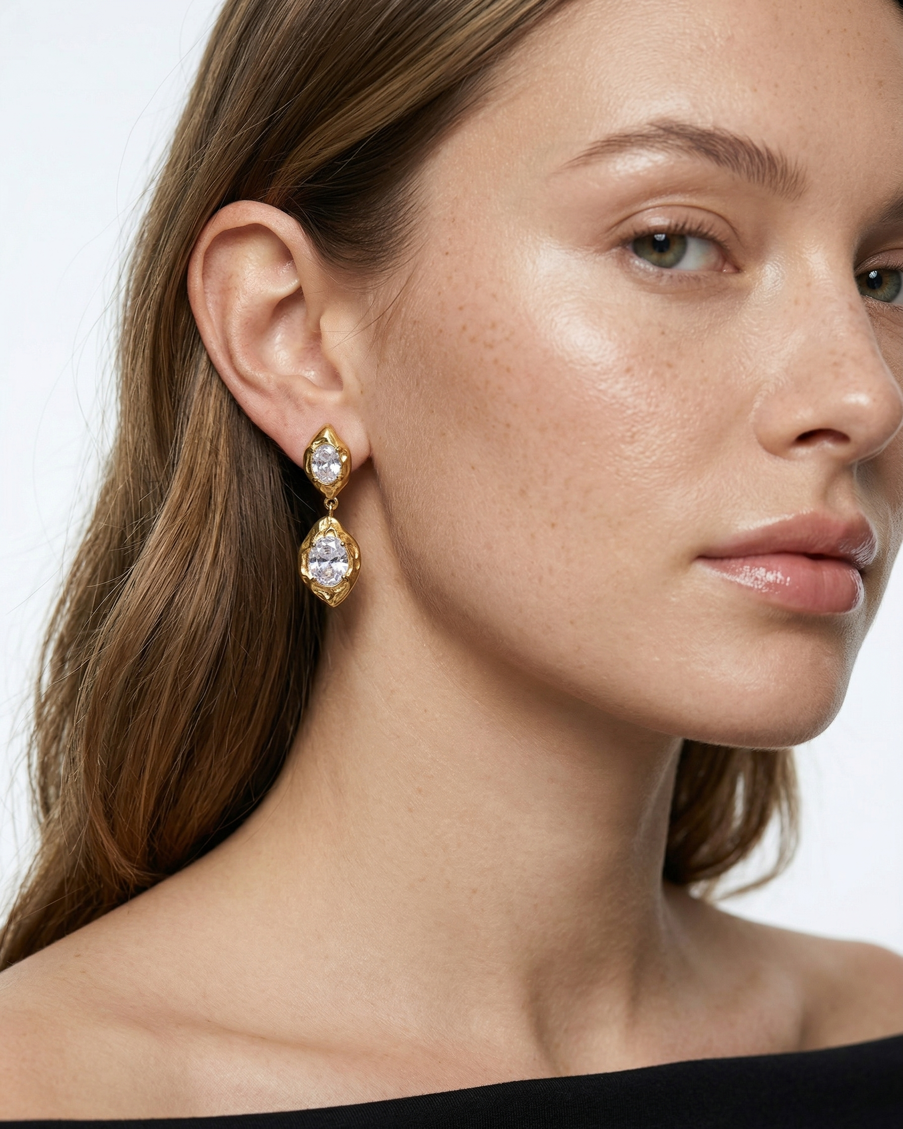 Close-up of a woman wearing gold earrings with a white background
