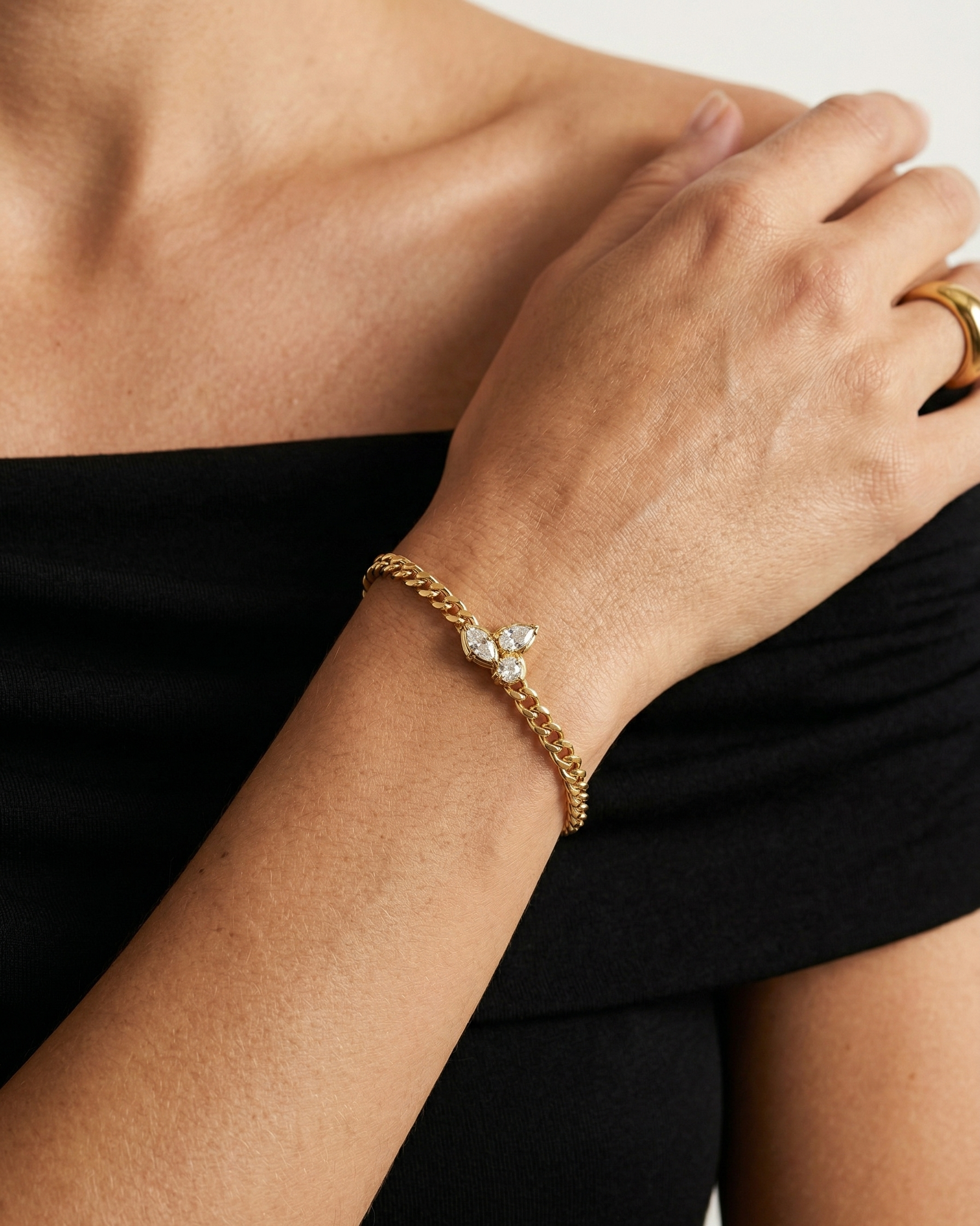 Gold bracelet with diamond accents on a person's wrist against a black background