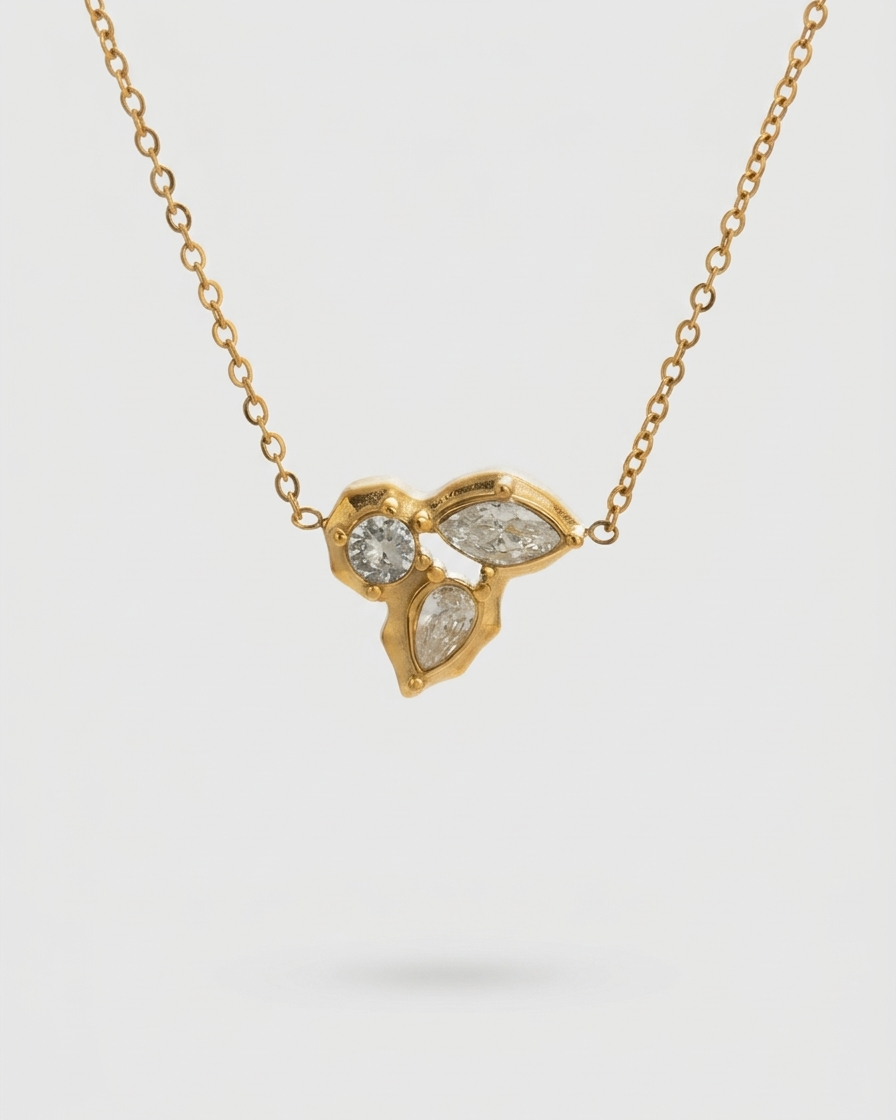 Gold necklace with a heart-shaped pendant featuring three diamonds on a light gray background