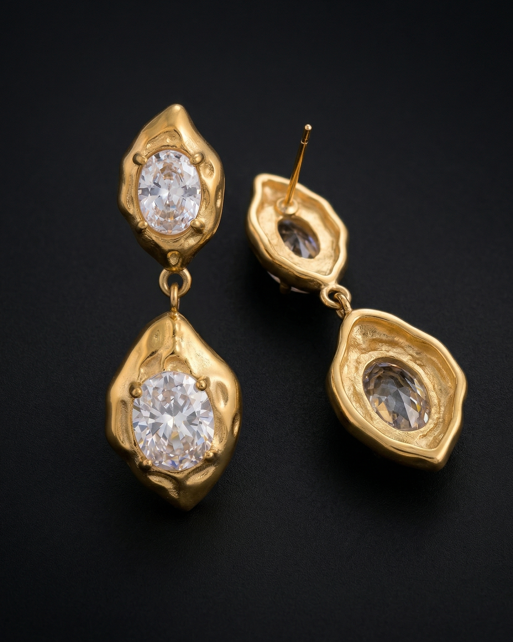 Gold earrings with clear gemstones on a black background