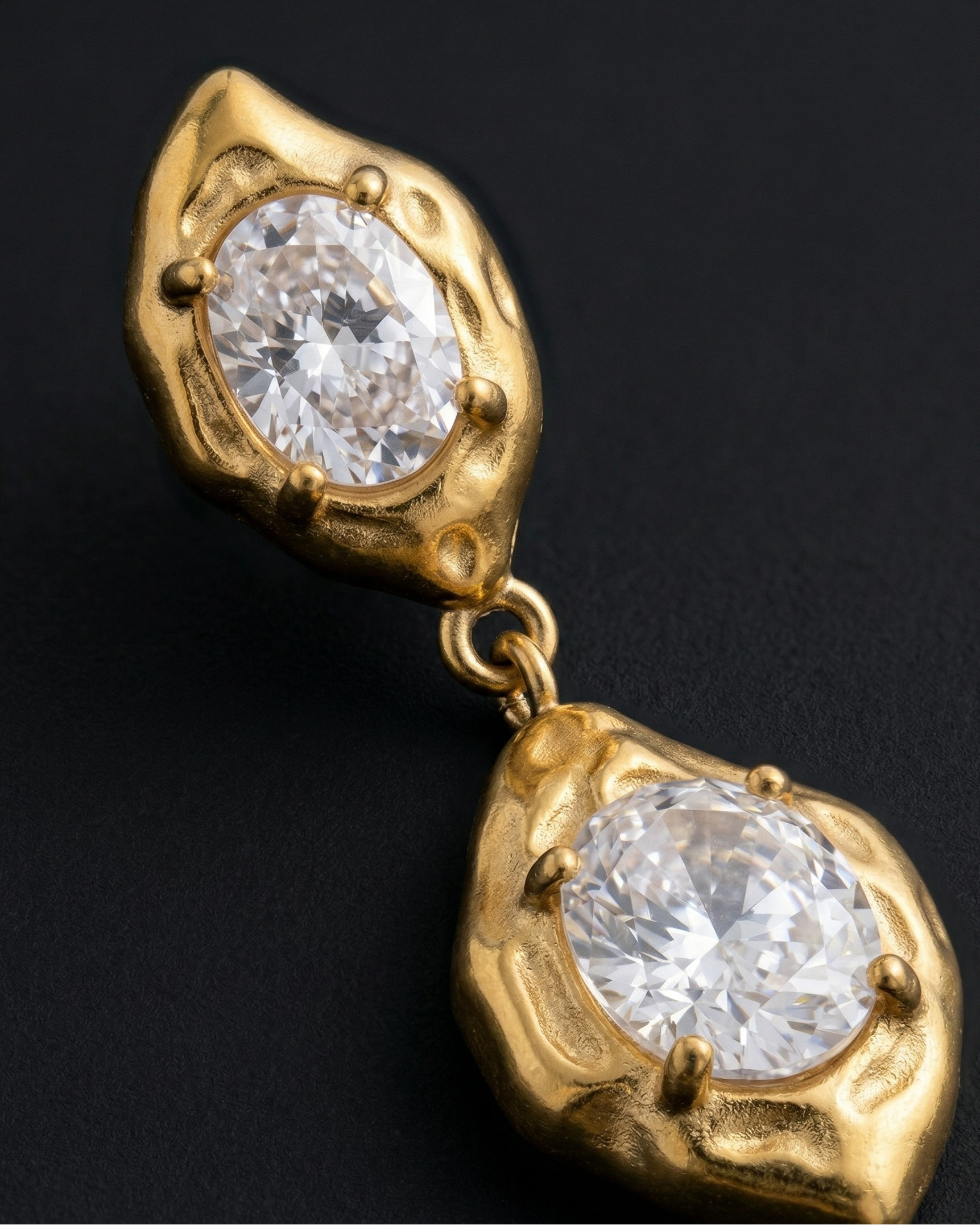 Gold earrings with clear gemstones on a black background