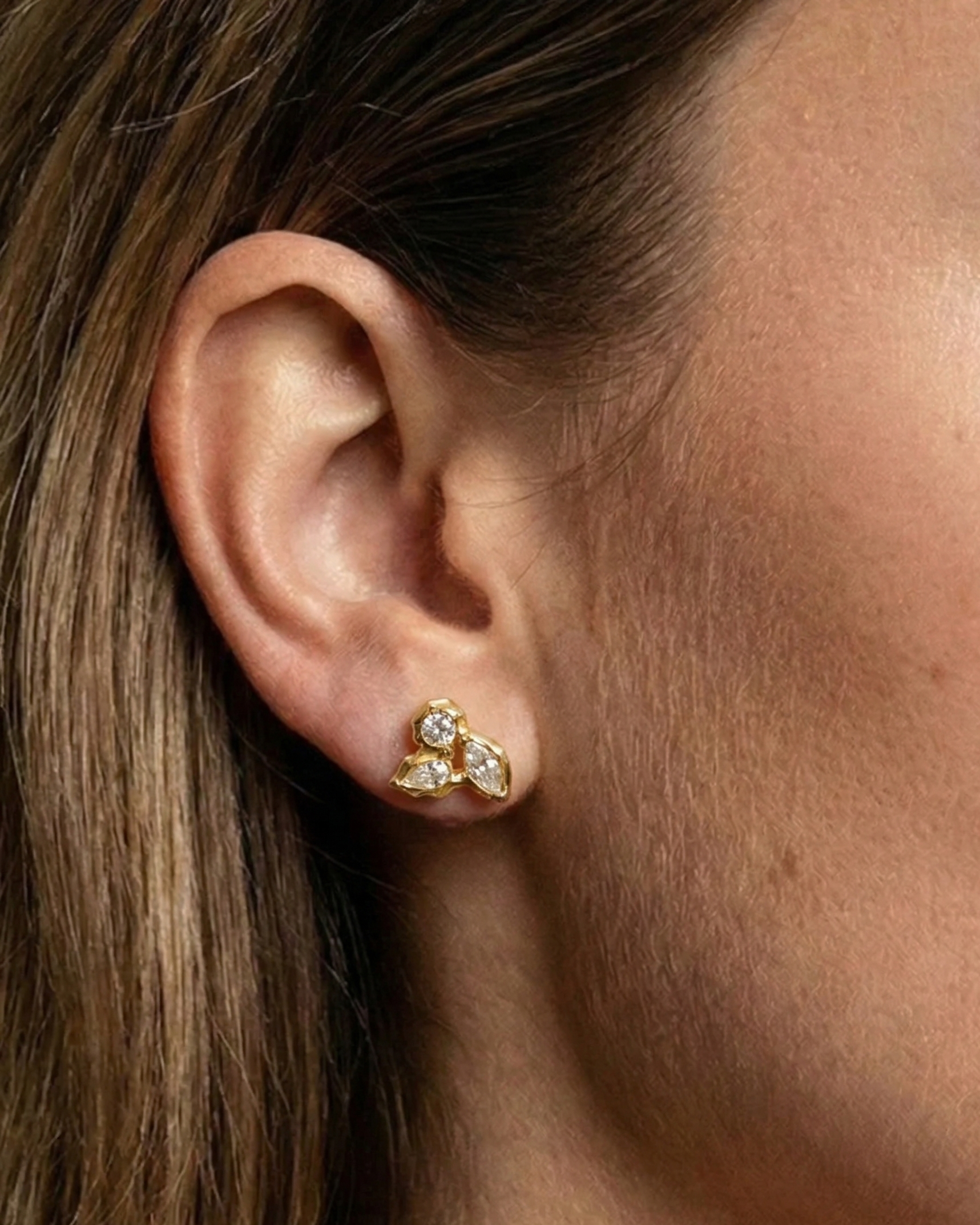 Close-up of an ear wearing a gold earring with a star design.