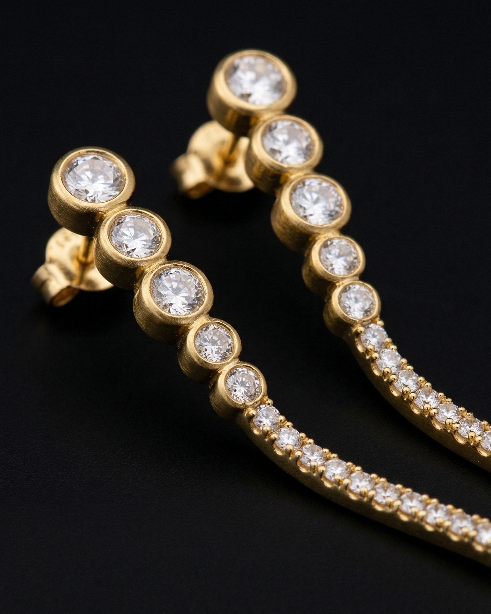 Gold hoop earrings with clear gemstones on a black background
