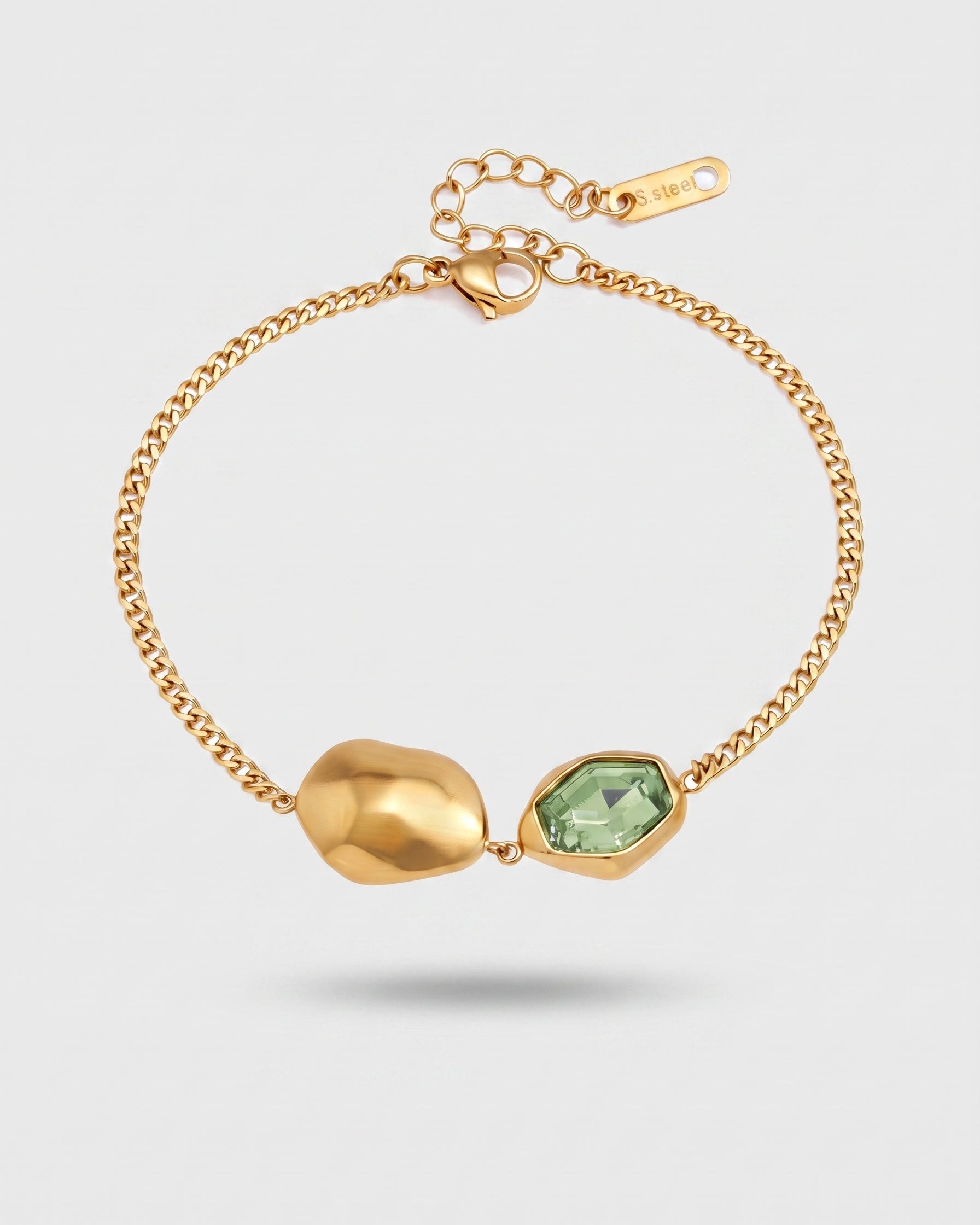 A gold chain bracelet featuring a polished gold abstract bead and a faceted light green gemstone bezel-set setting, displayed on a light gray background.