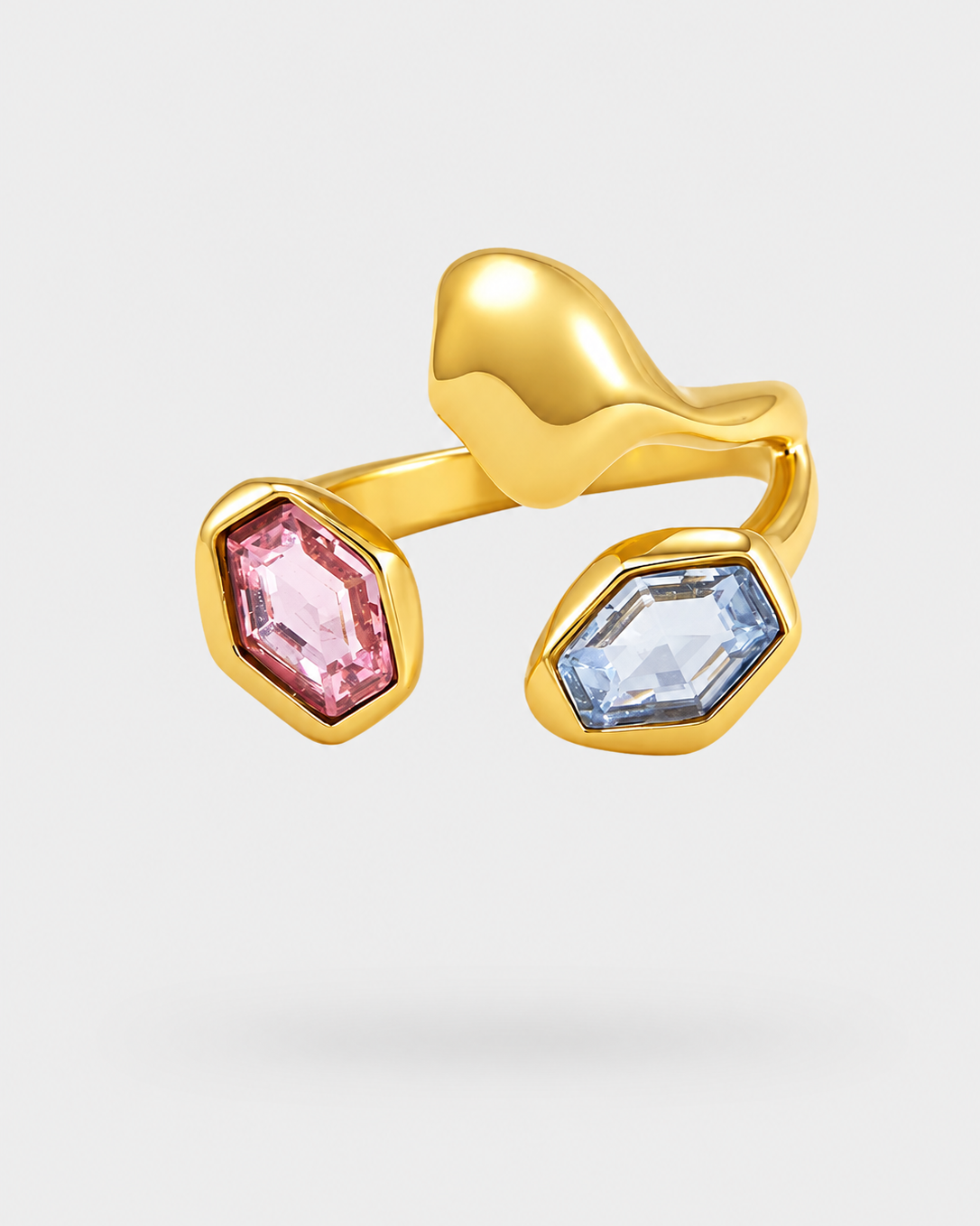 A gold-plated open ring featuring two hexagonal gemstones, one pink and one light blue, set against a light gray background.