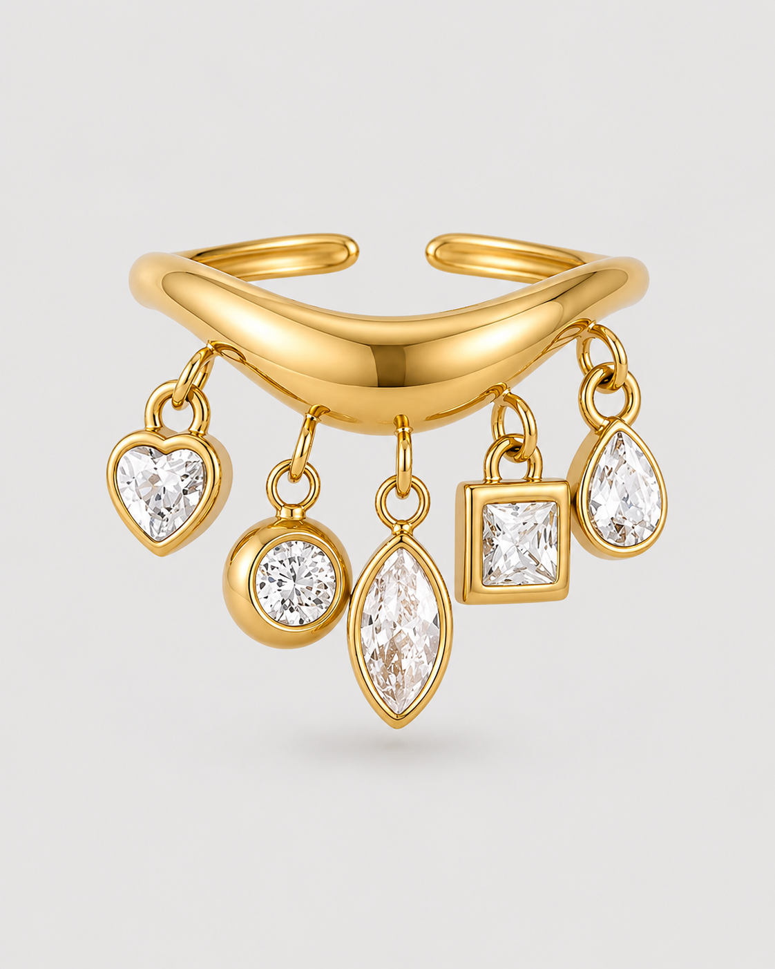 Gold-toned open cuff ring with five dangling clear gemstones in heart, round, marquise, square, and teardrop shapes, shown on a light gray background.