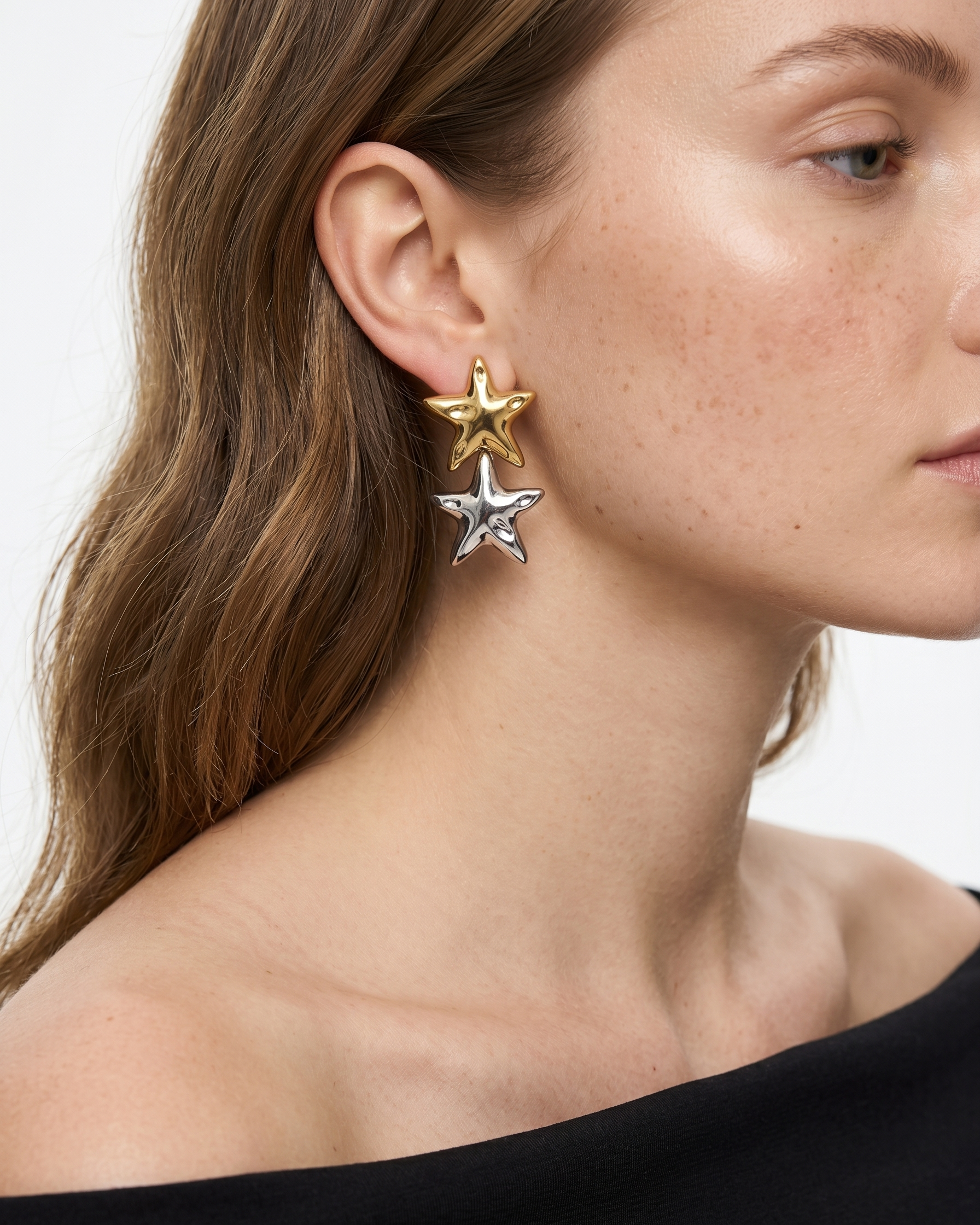 Close-up of a woman wearing star-shaped earrings on a plain background