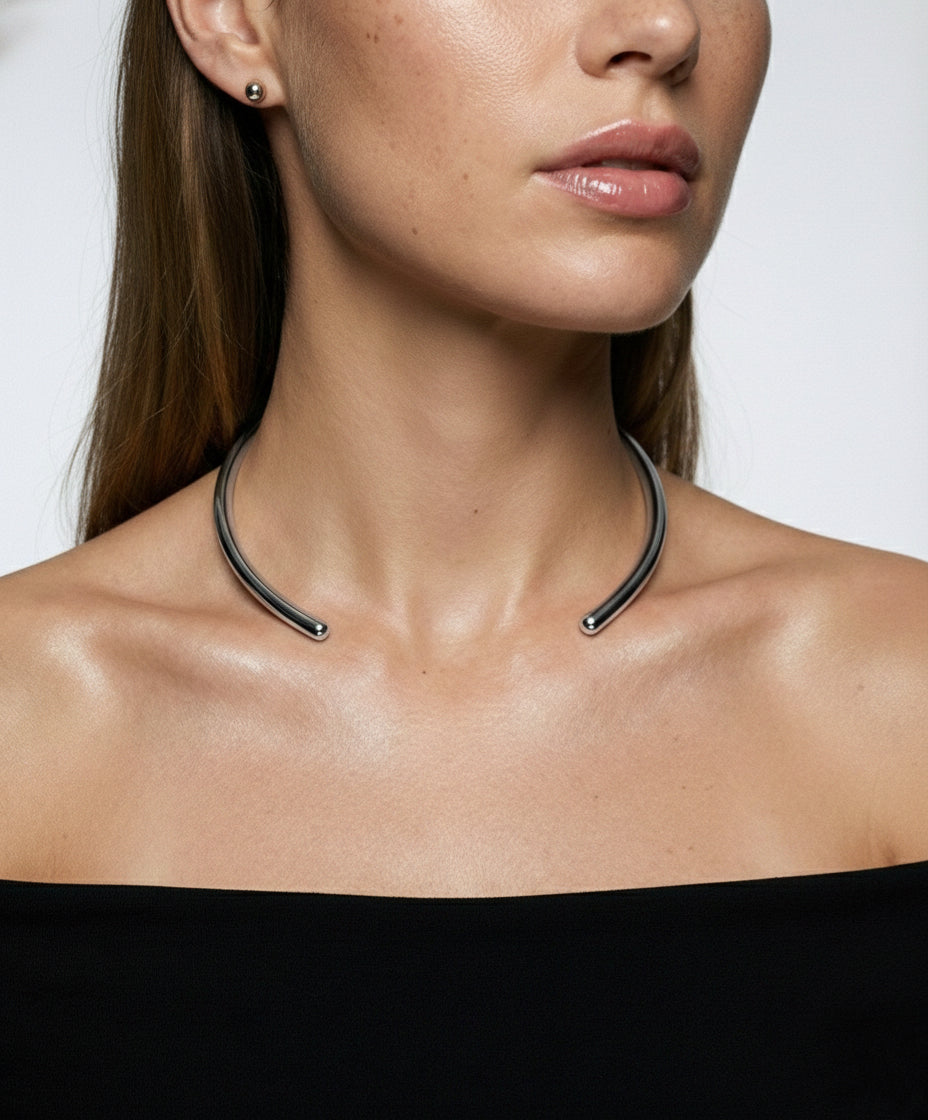 Close-up of a woman wearing a unique necklace against a plain background