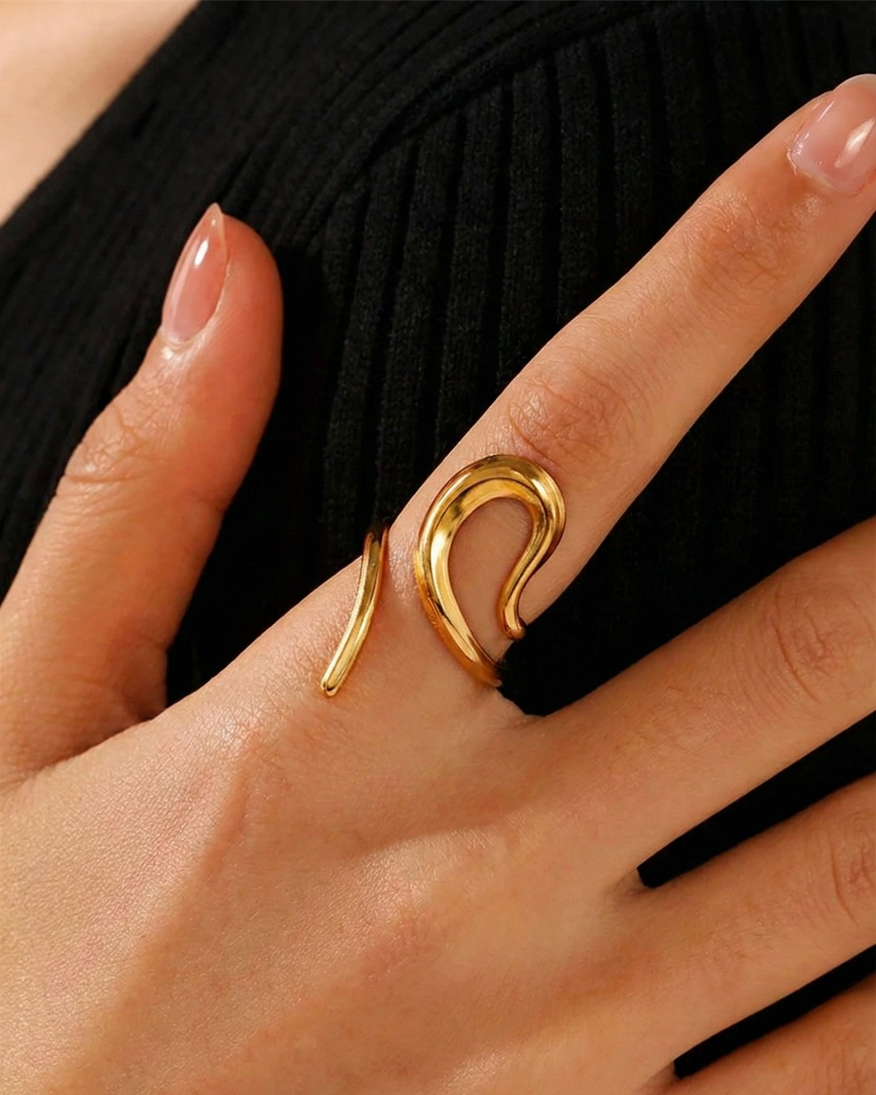 Gold ring on a person's finger against a black background