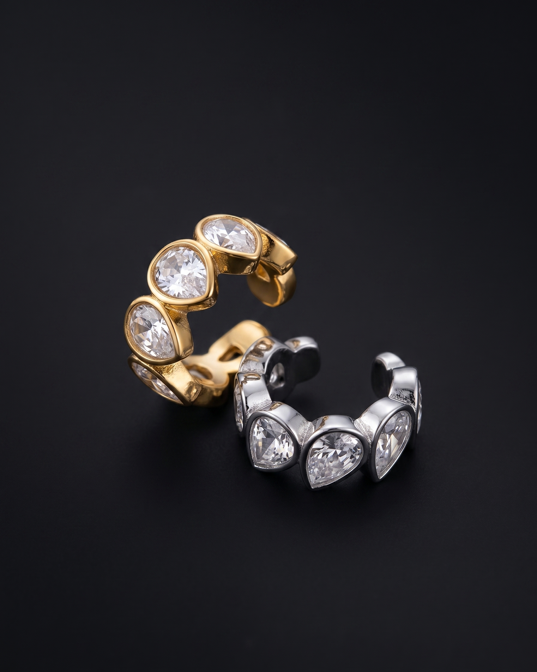 Gold and silver ear cuffs with gemstones on a black background