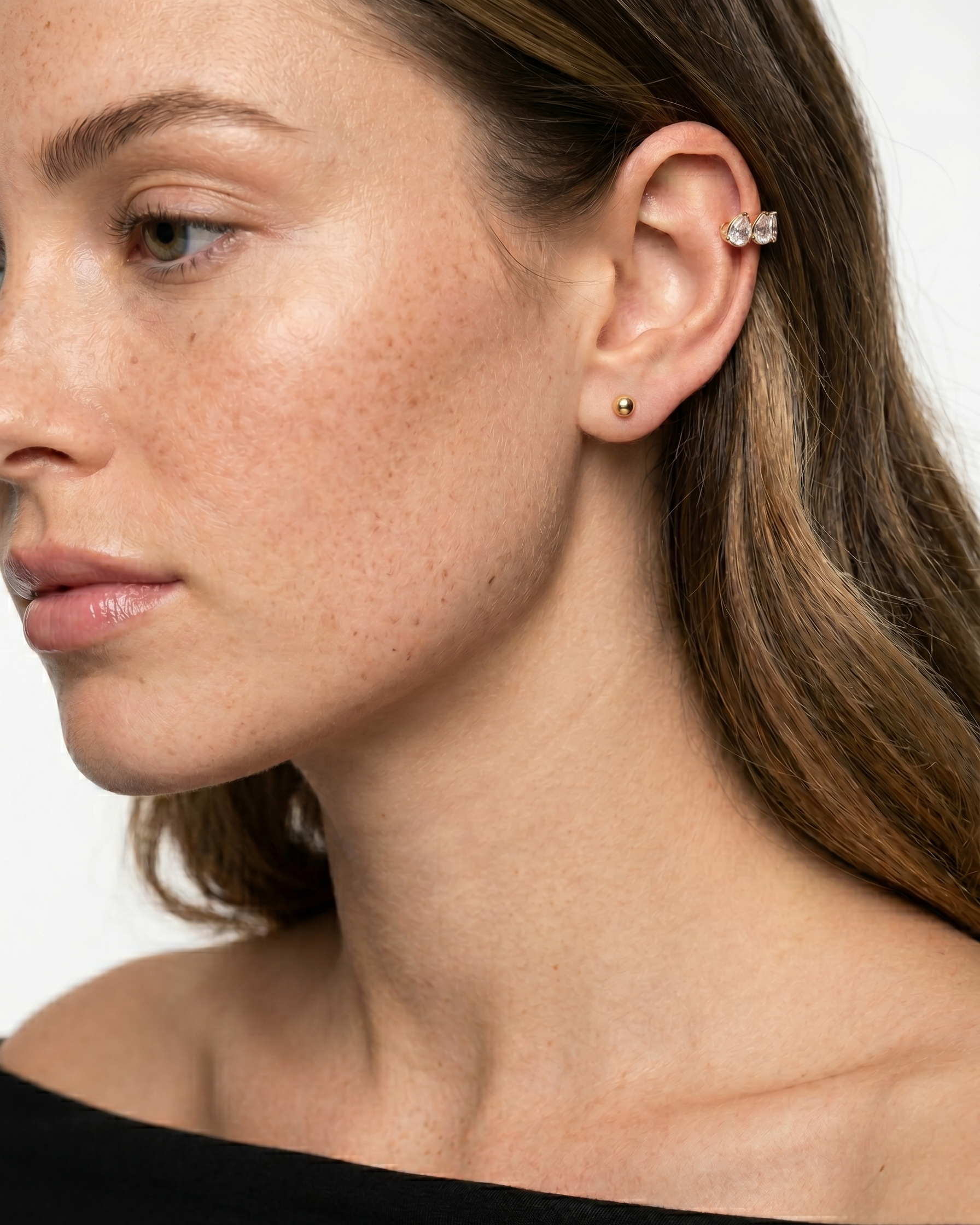 Close-up of a woman wearing gold earrings with a plain background