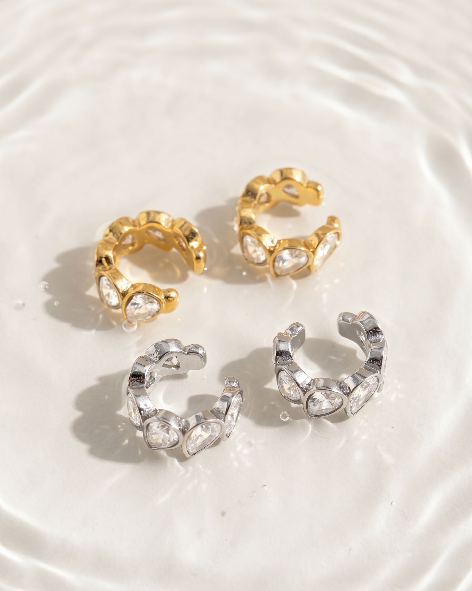 Gold and silver hoop earrings on a textured white surface