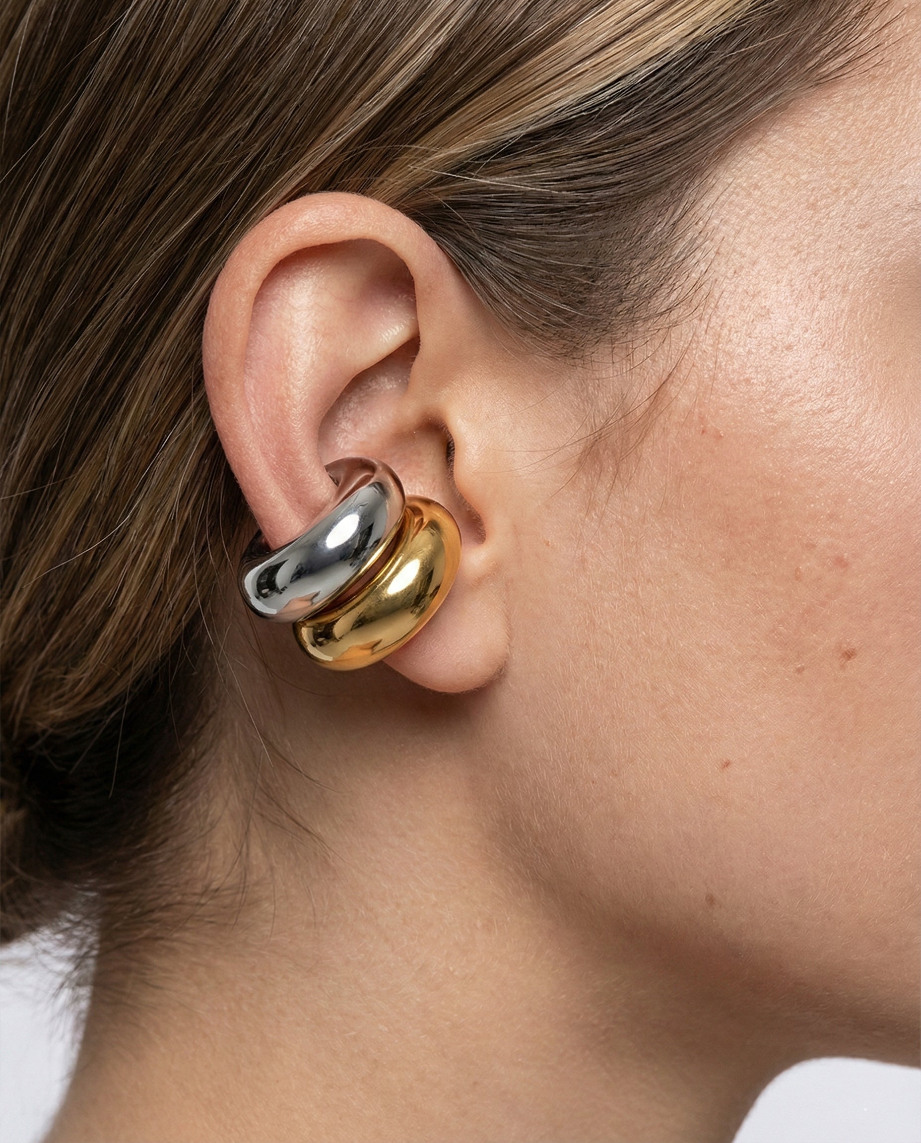 Close-up of an ear wearing a gold and silver earring.