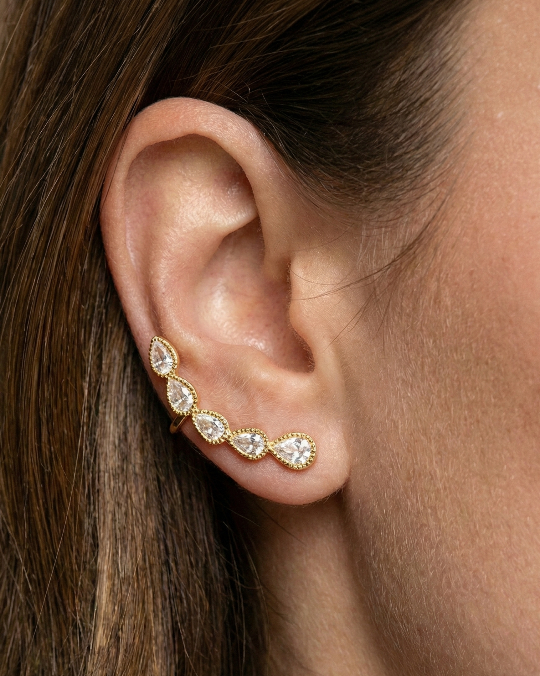 Gold earring with clear stones worn by a person