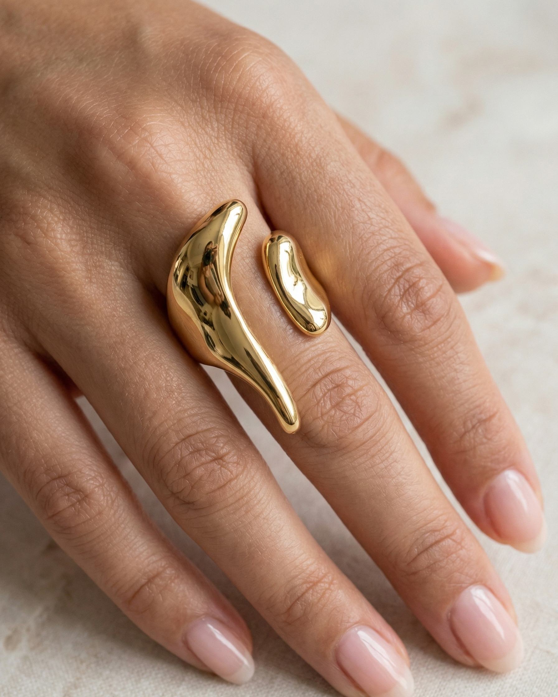 Gold ring on a hand with a neutral background