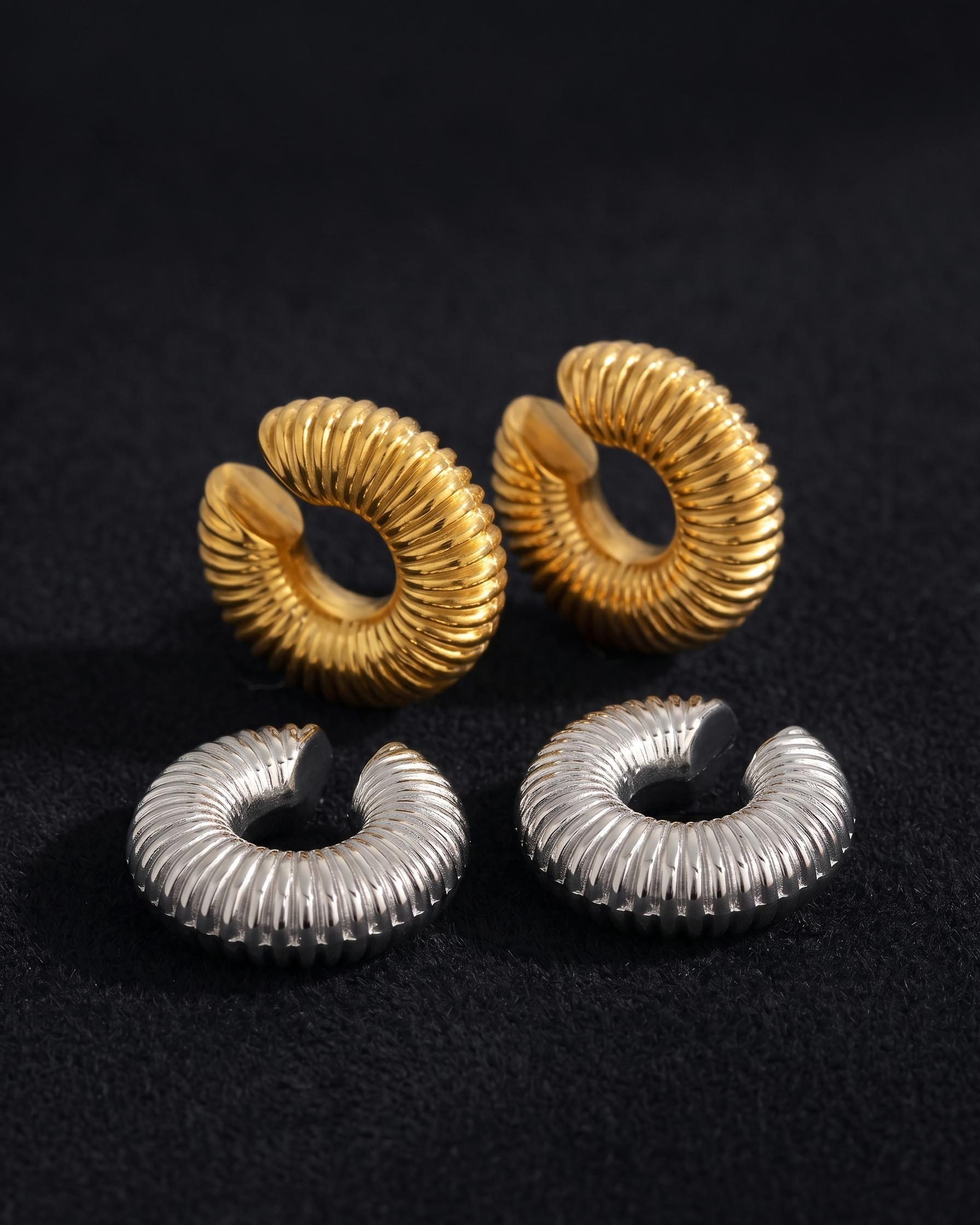 Pair of gold and silver spiral earrings on a black background