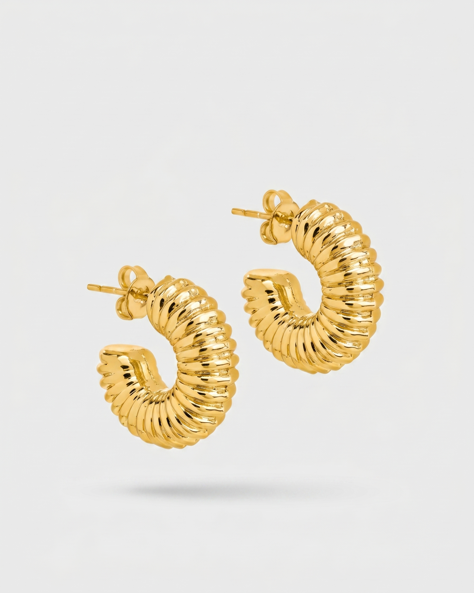 Gold hoop earrings on a light gray background