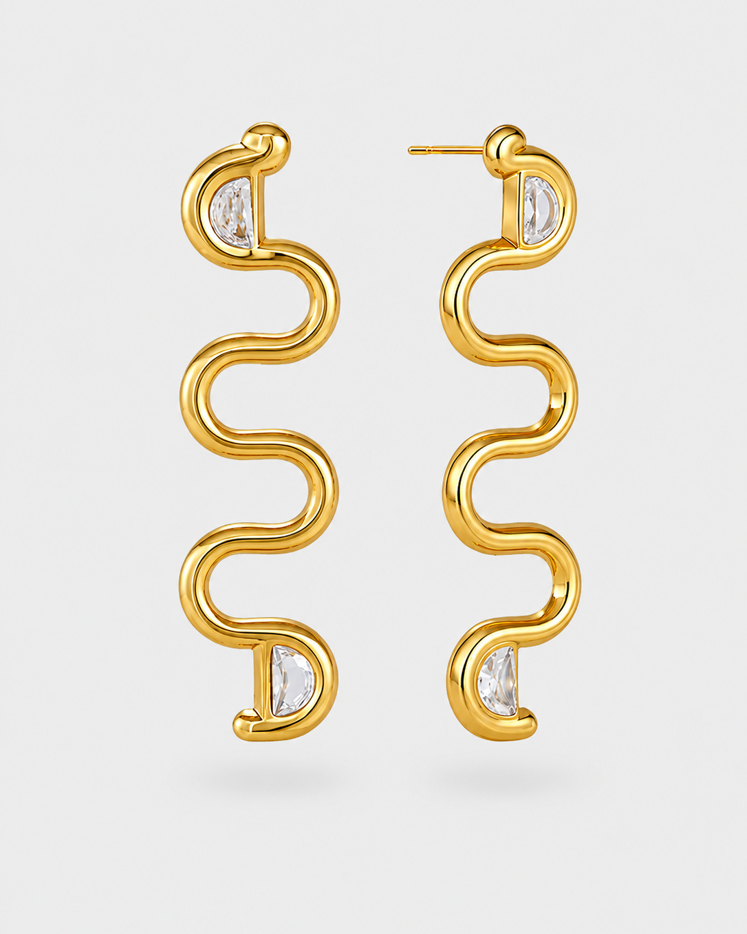 A pair of gold S-shaped dangle earrings with small clear marquise-cut gemstones at the bottom of each earring, shown against a light gray background.