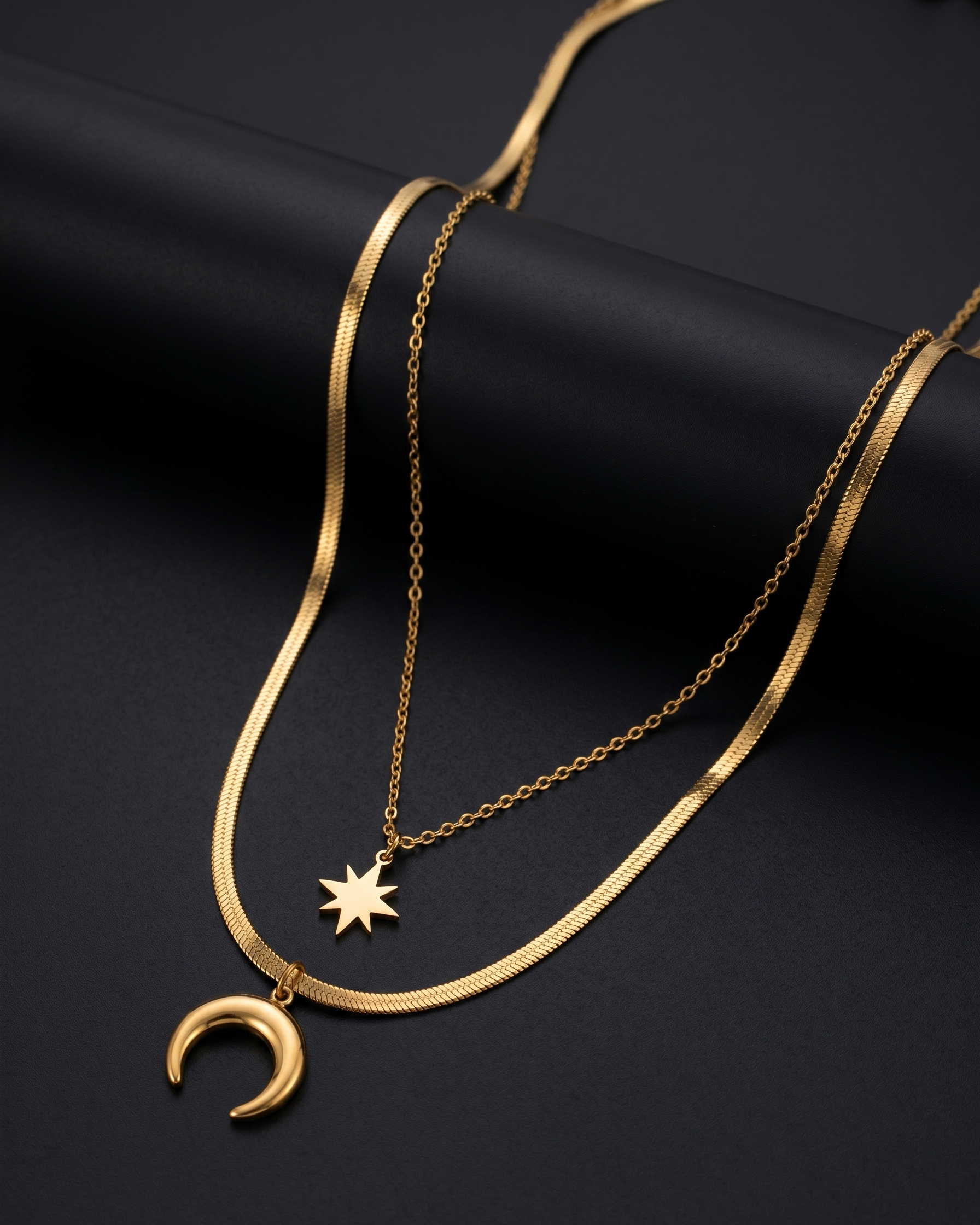 Gold necklace with star and moon pendants on a black background