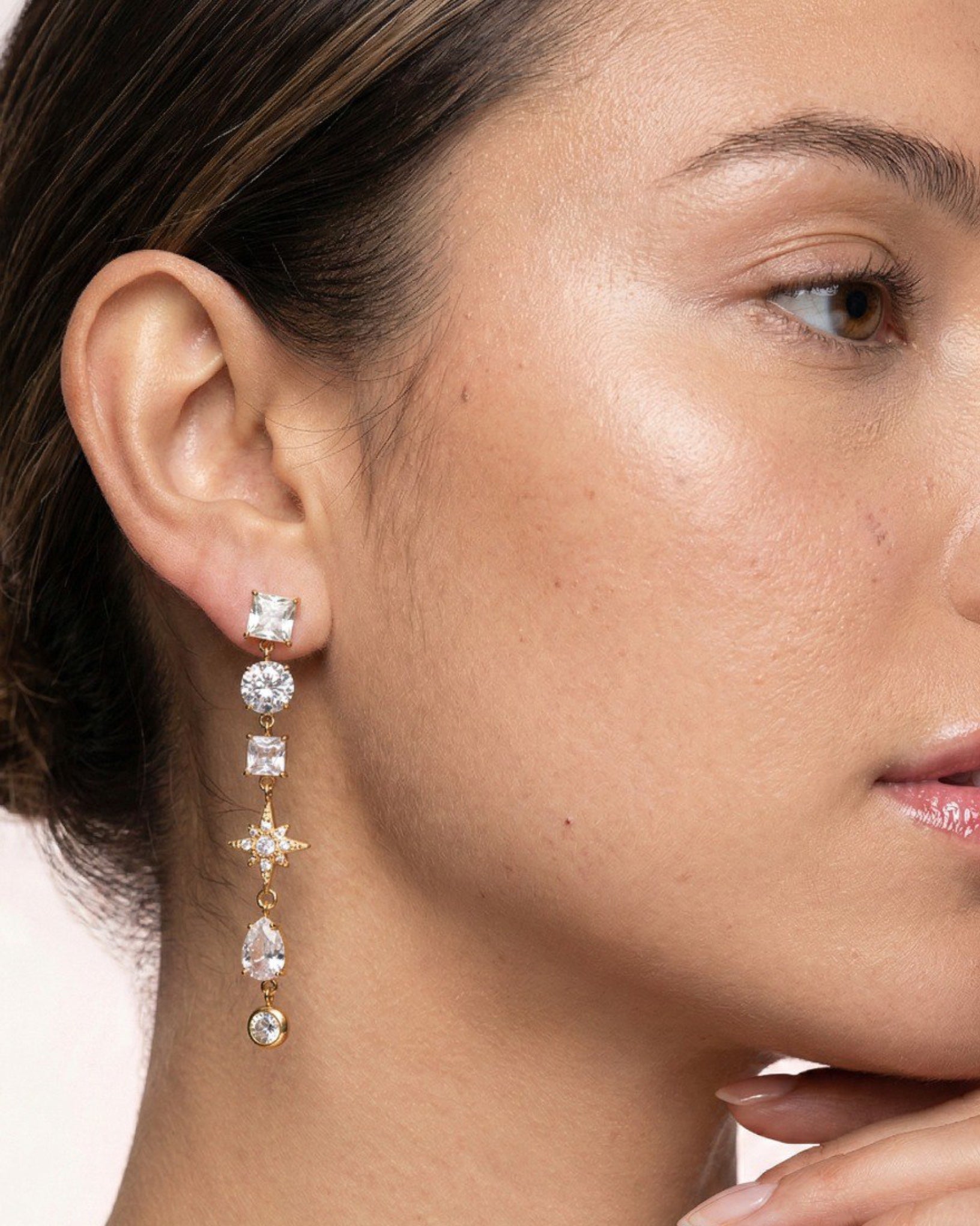 Close-up of a woman wearing a set of earrings with a neutral background