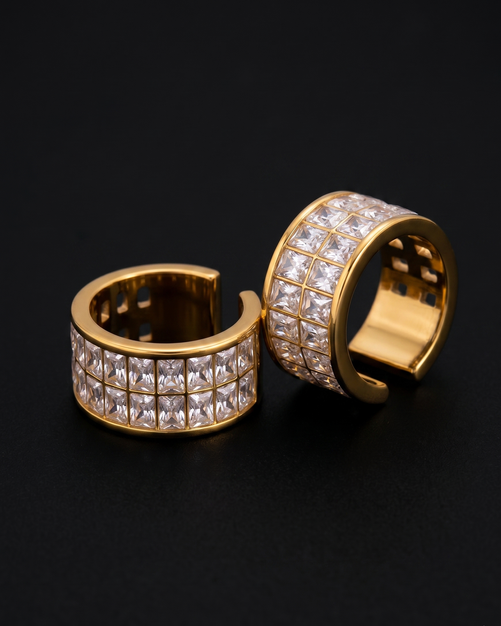 Gold hoop earrings with clear gemstones on a black background