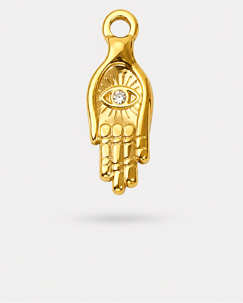 A gold Hamsa hand charm pendant featuring a small clear gemstone eye at the center, shown against a light gray background.