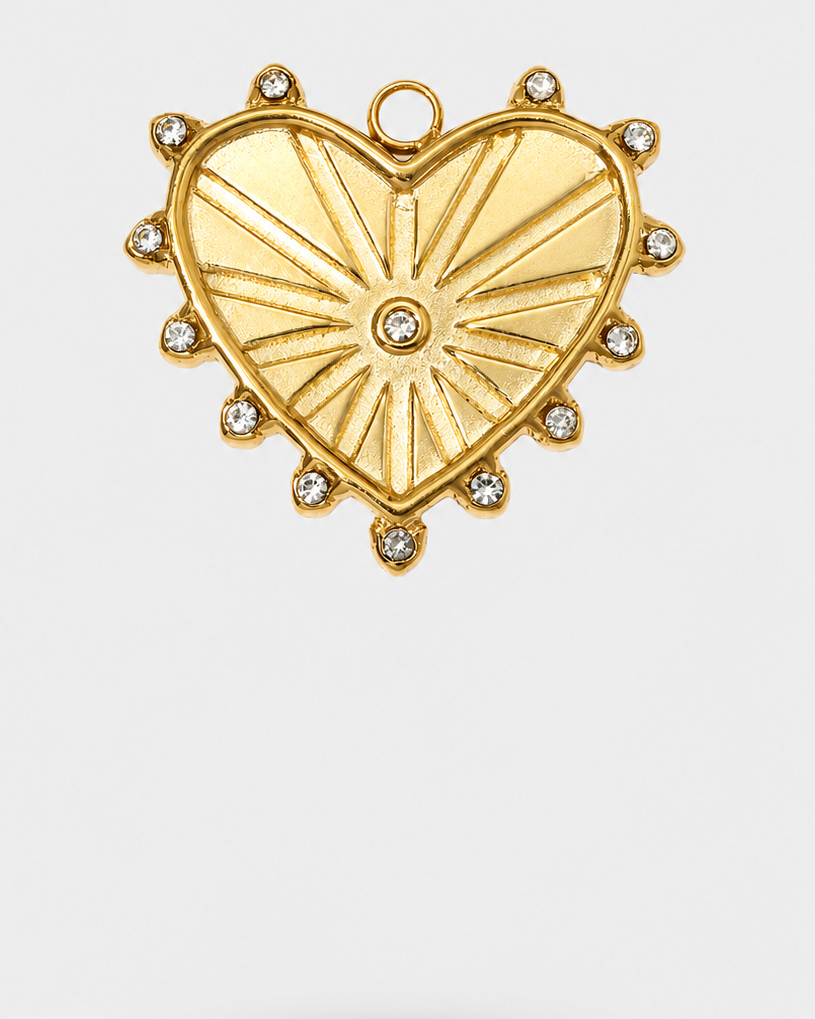 A gold heart-shaped pendant charm with a sunburst design, accented by small clear rhinestones along the border and a central stone, shown on a light gray background.