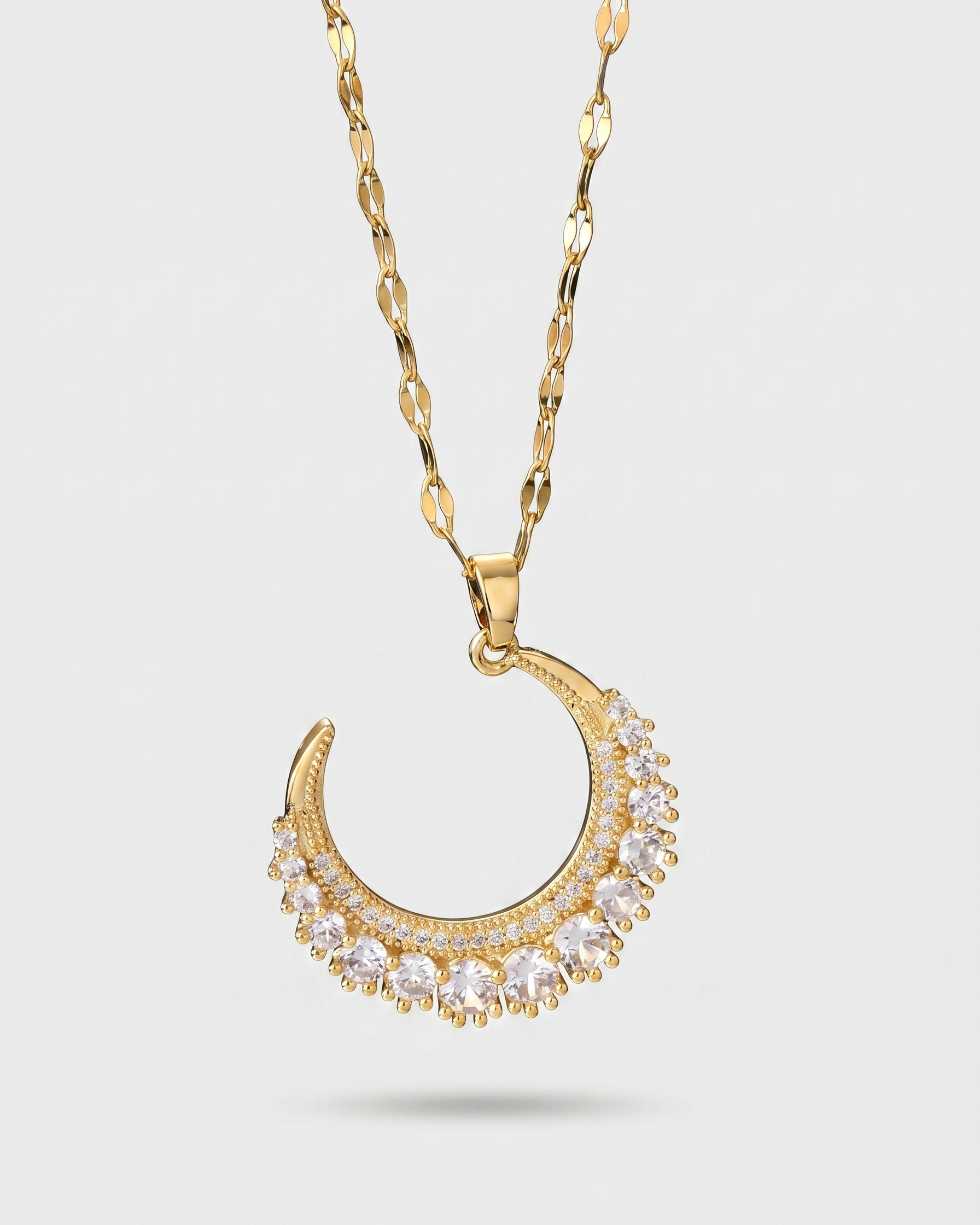 Gold necklace with a crescent moon pendant on a light gray background