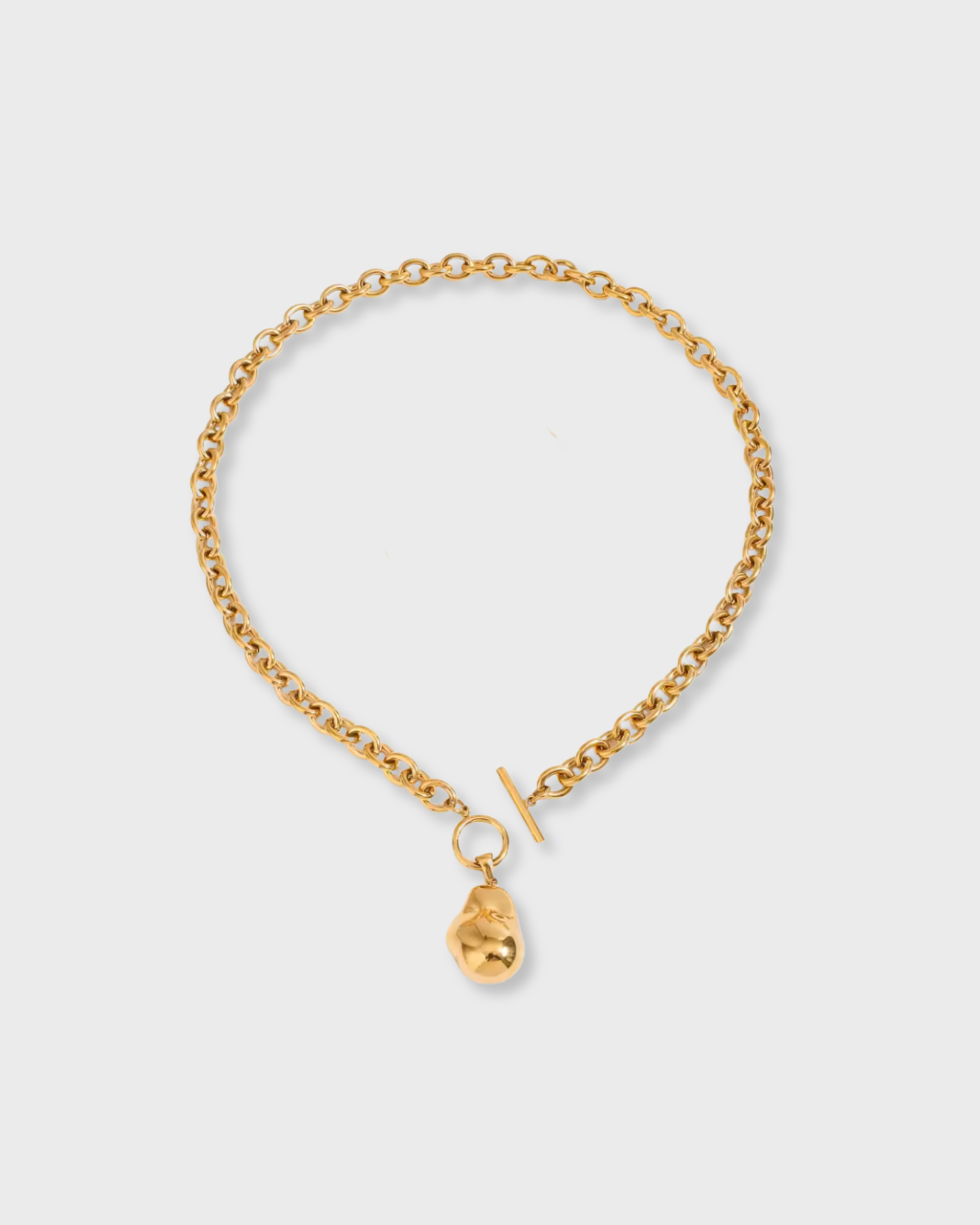 Gold chain bracelet with a small gold charm on a light gray background