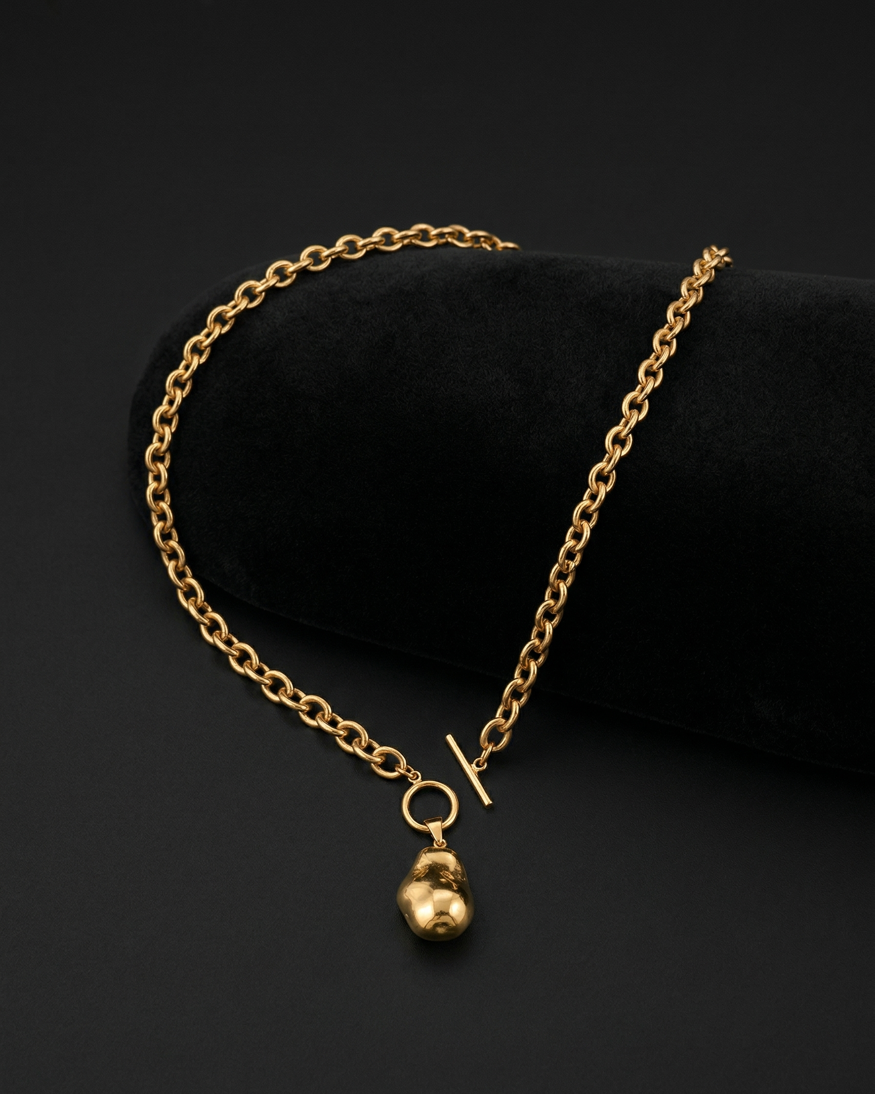 Gold chain necklace with a small pendant on a black background