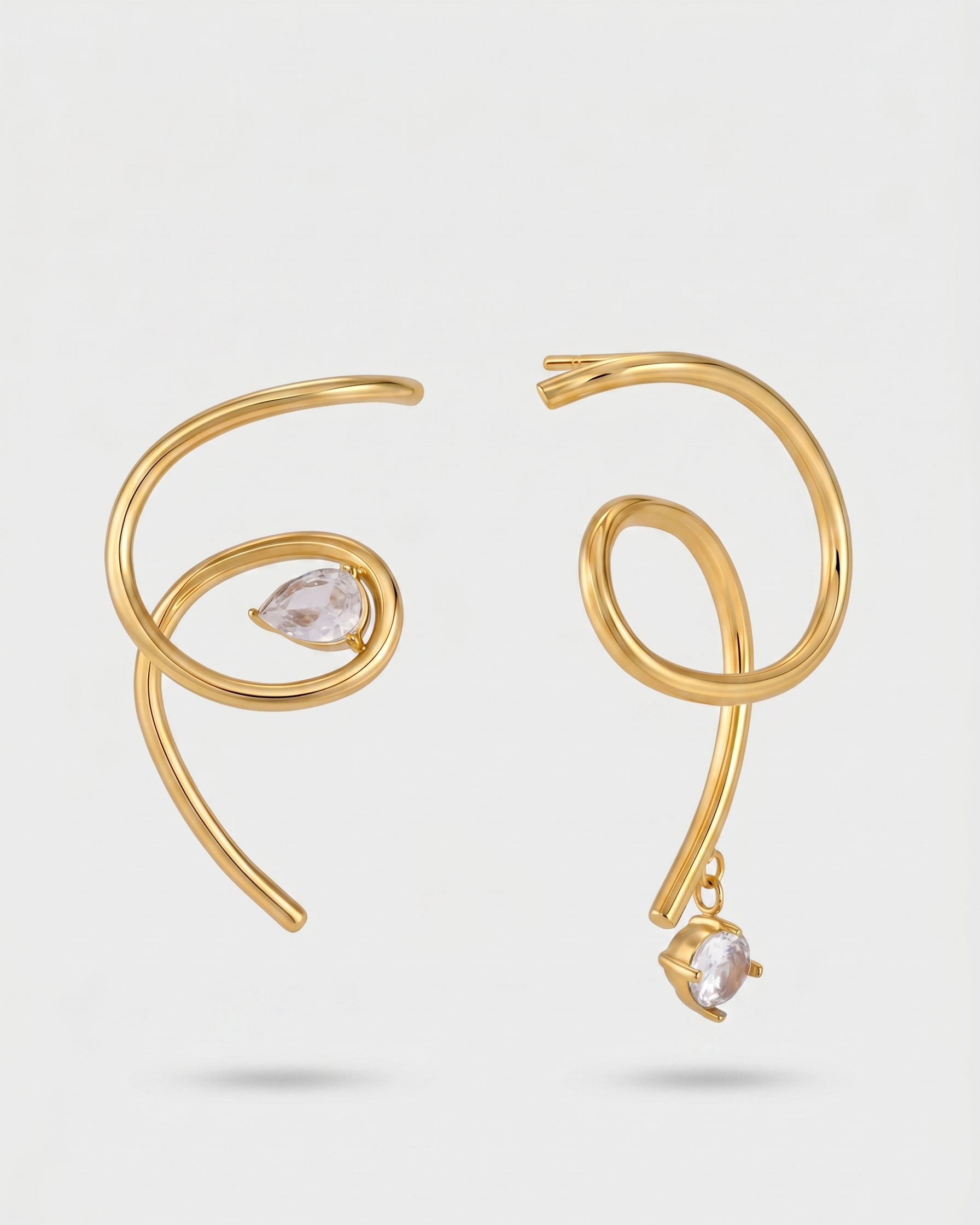 Gold spiral earrings with clear gemstones on a light gray background