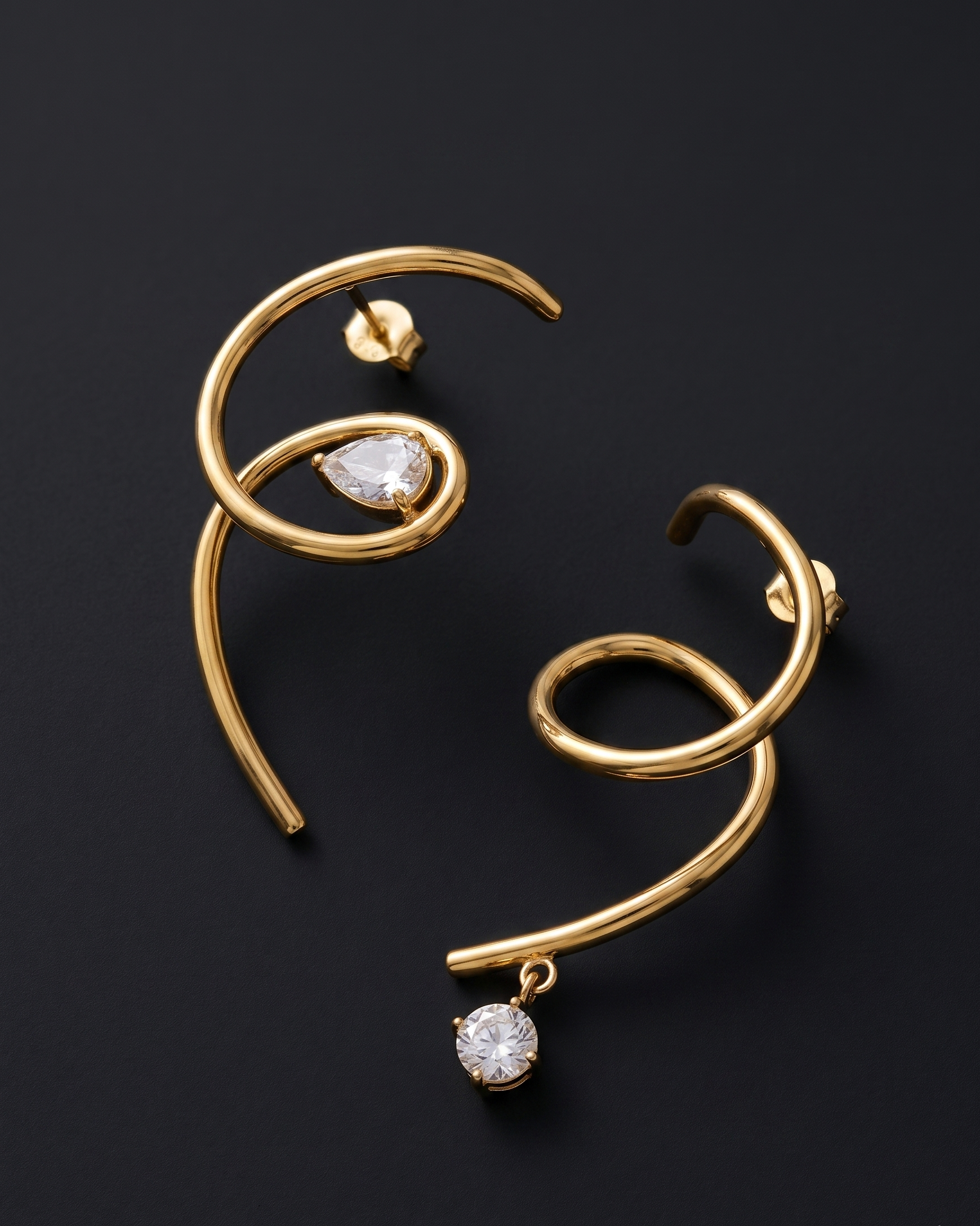 Gold earrings with clear gemstones on a dark background