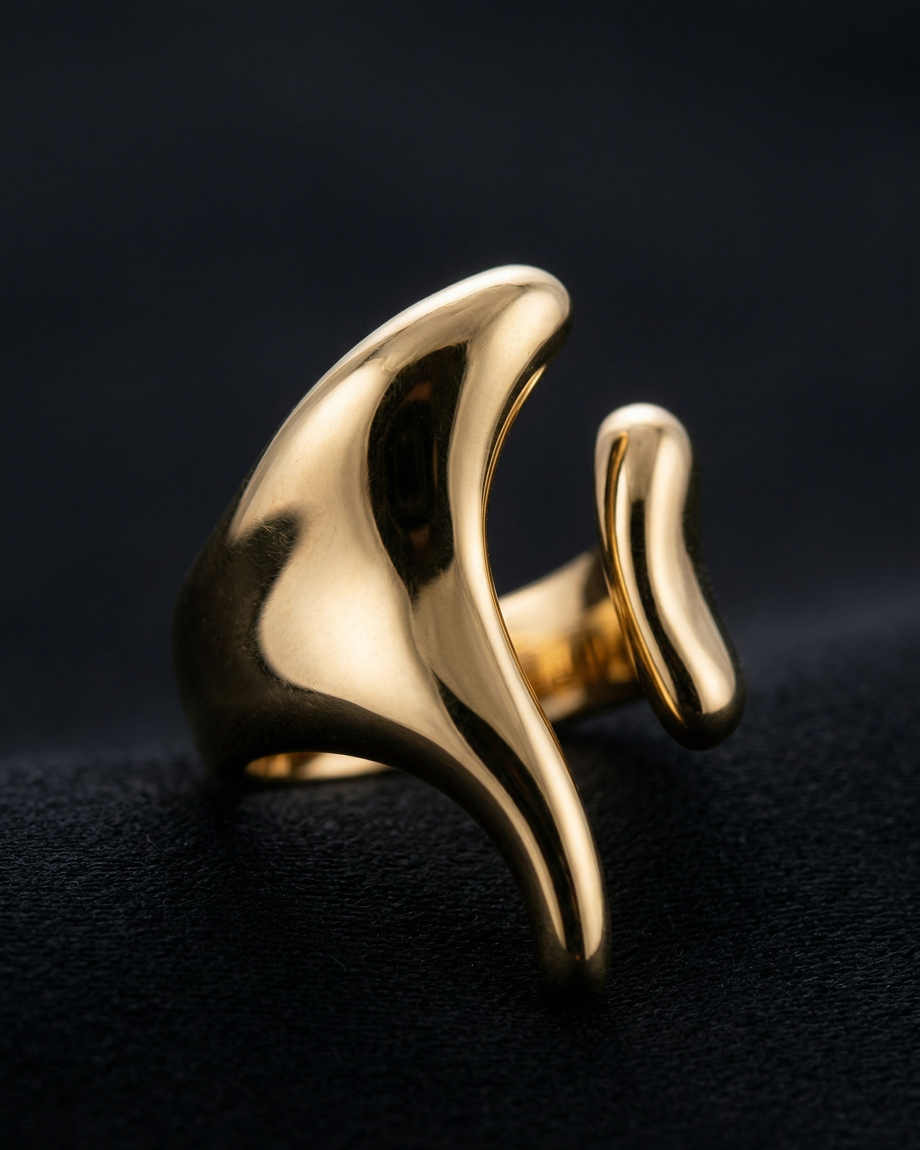 Gold ring with wavy design on a black background