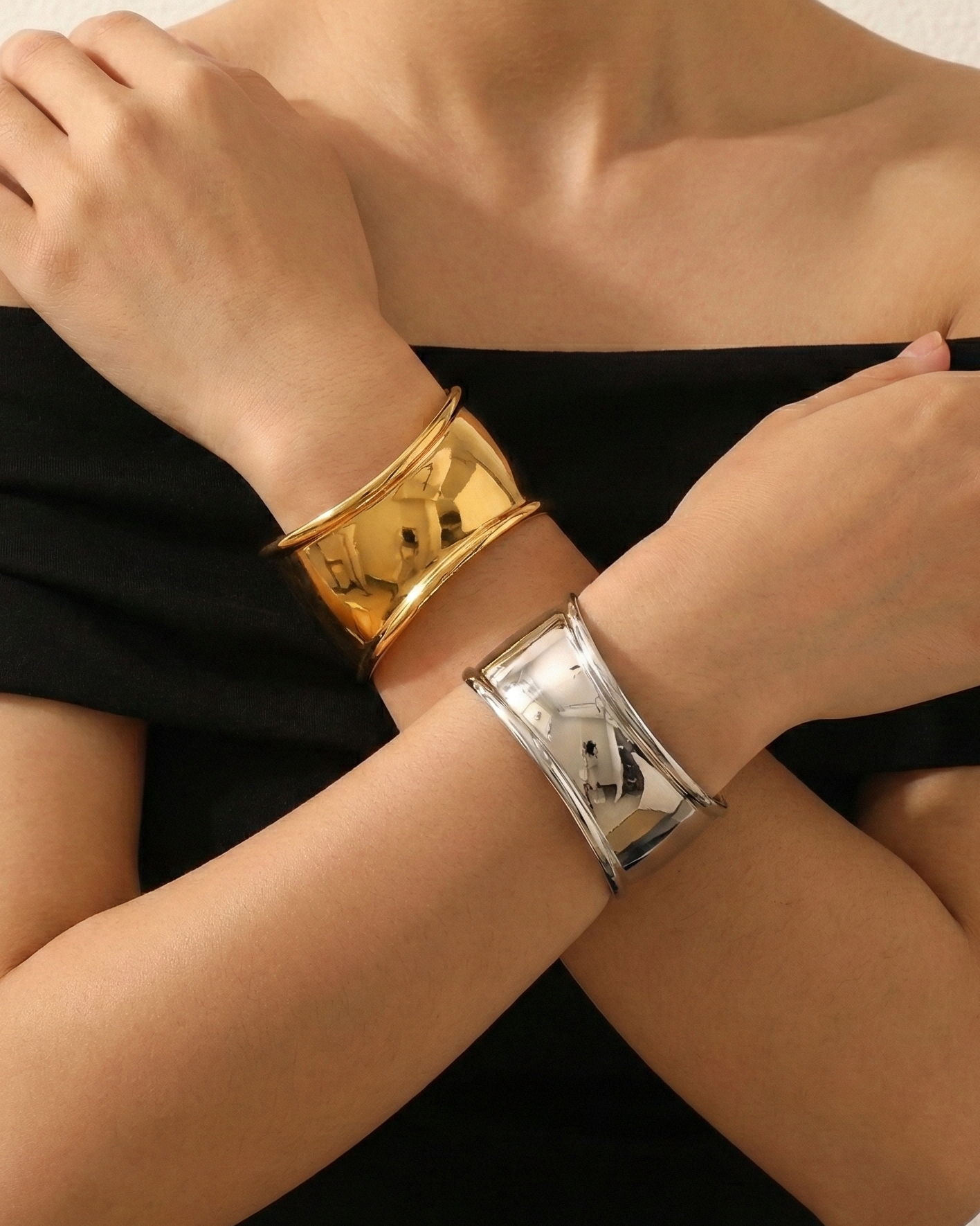 Person wearing gold and silver bracelets on a plain background