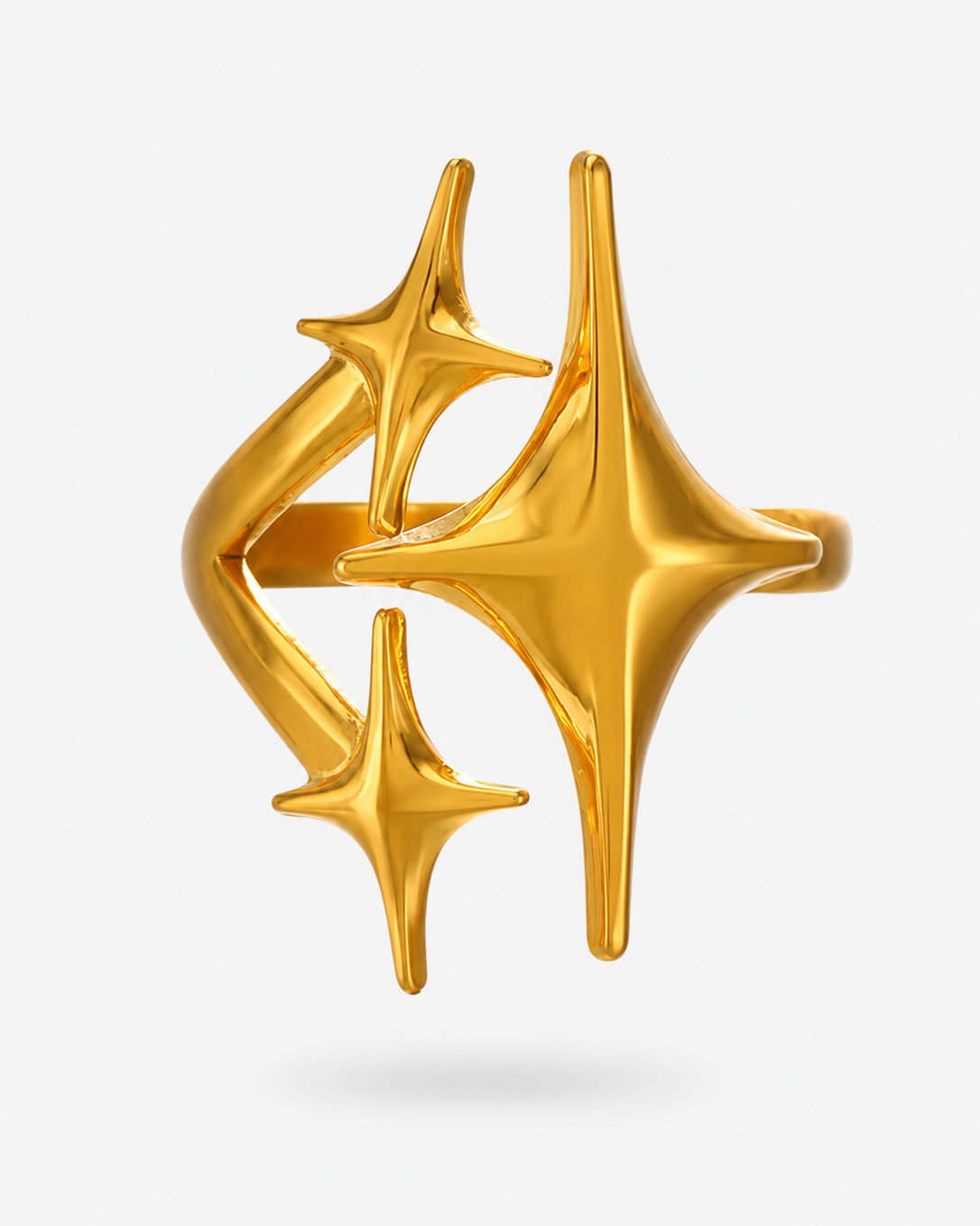 A gold ring featuring three stylized, open starburst or sparkle shapes, photographed against a clean light gray background.