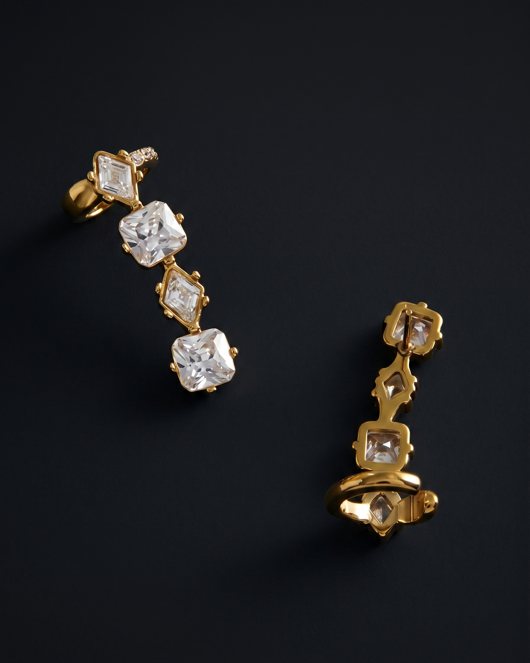 Gold earrings with diamond-like stones on a dark background