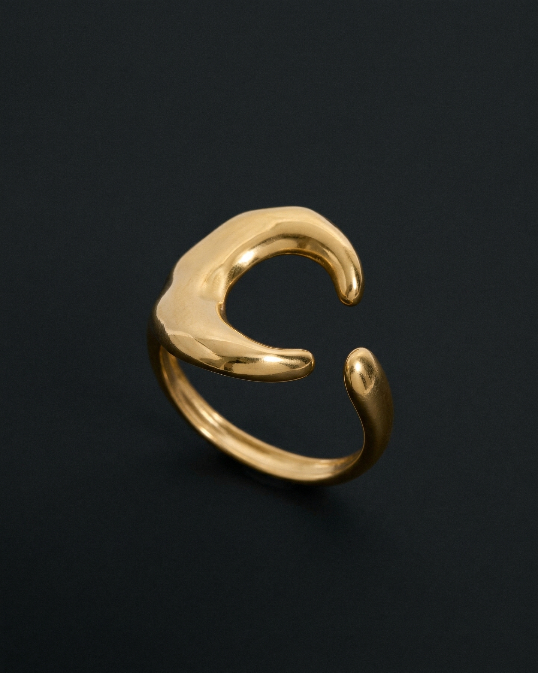 Gold ring with a unique design on a black background