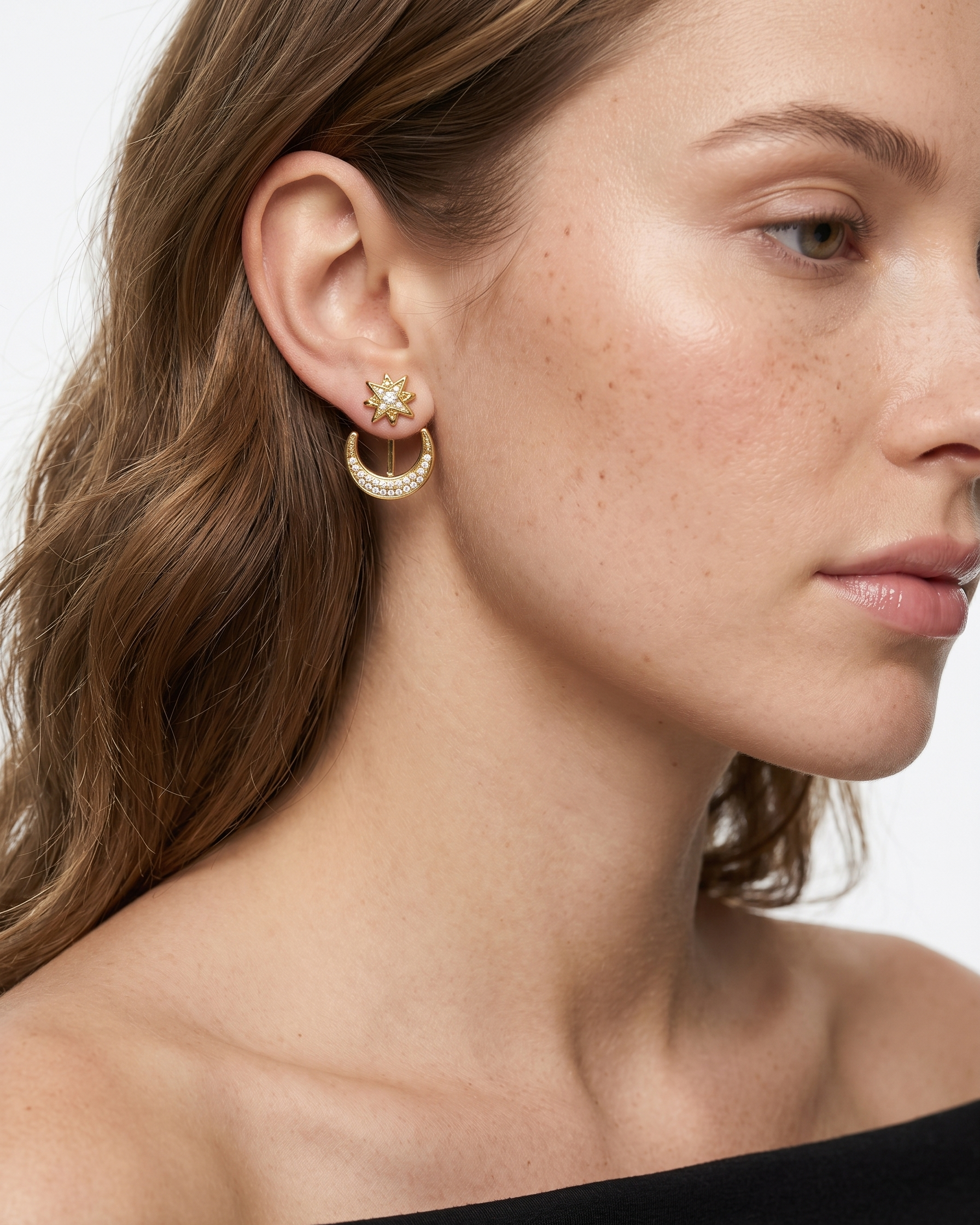 Close-up of a woman wearing gold hoop earrings with a star detail.