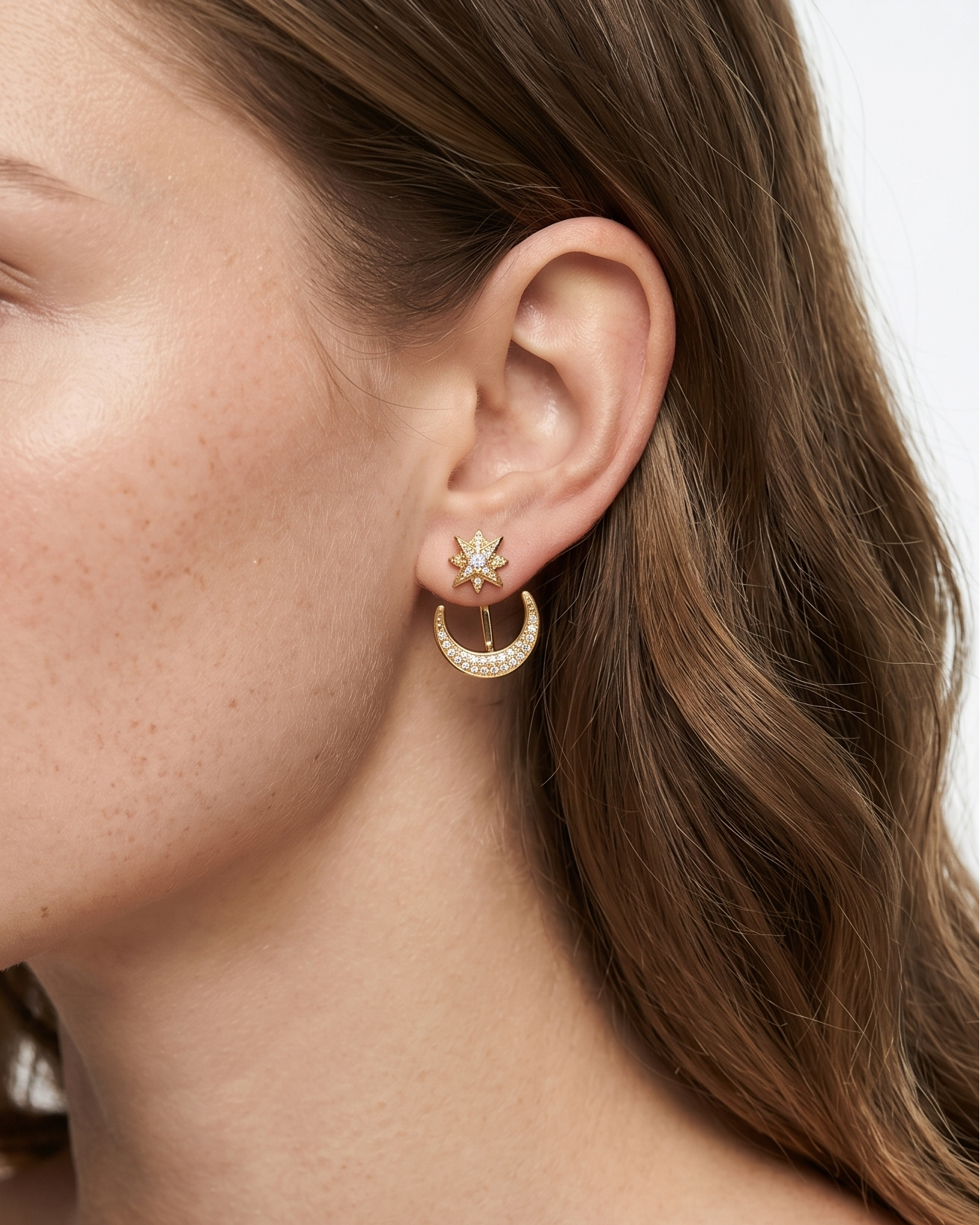 Close-up of a woman wearing gold hoop earrings with a neutral background