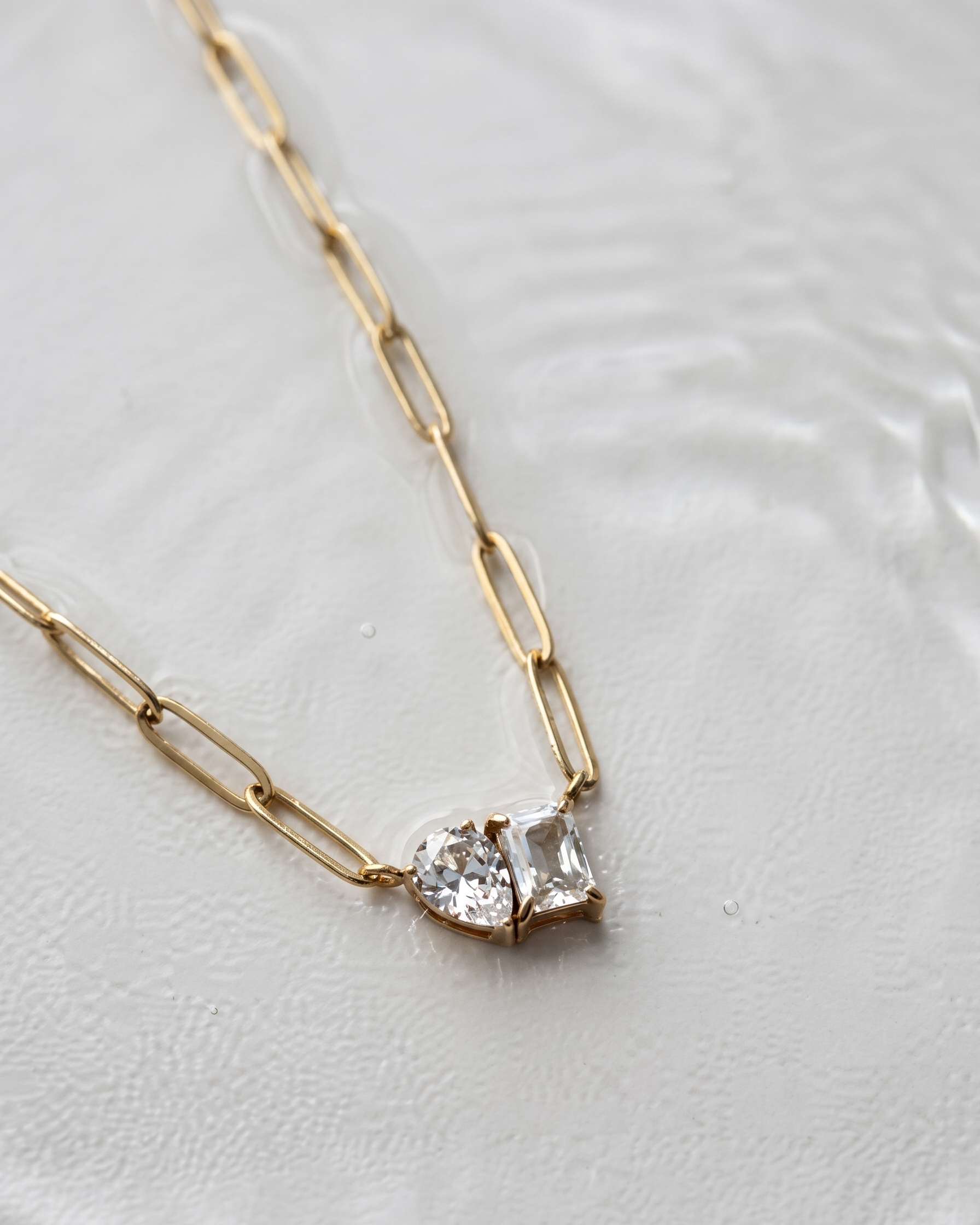 Gold necklace with a diamond pendant on a light background