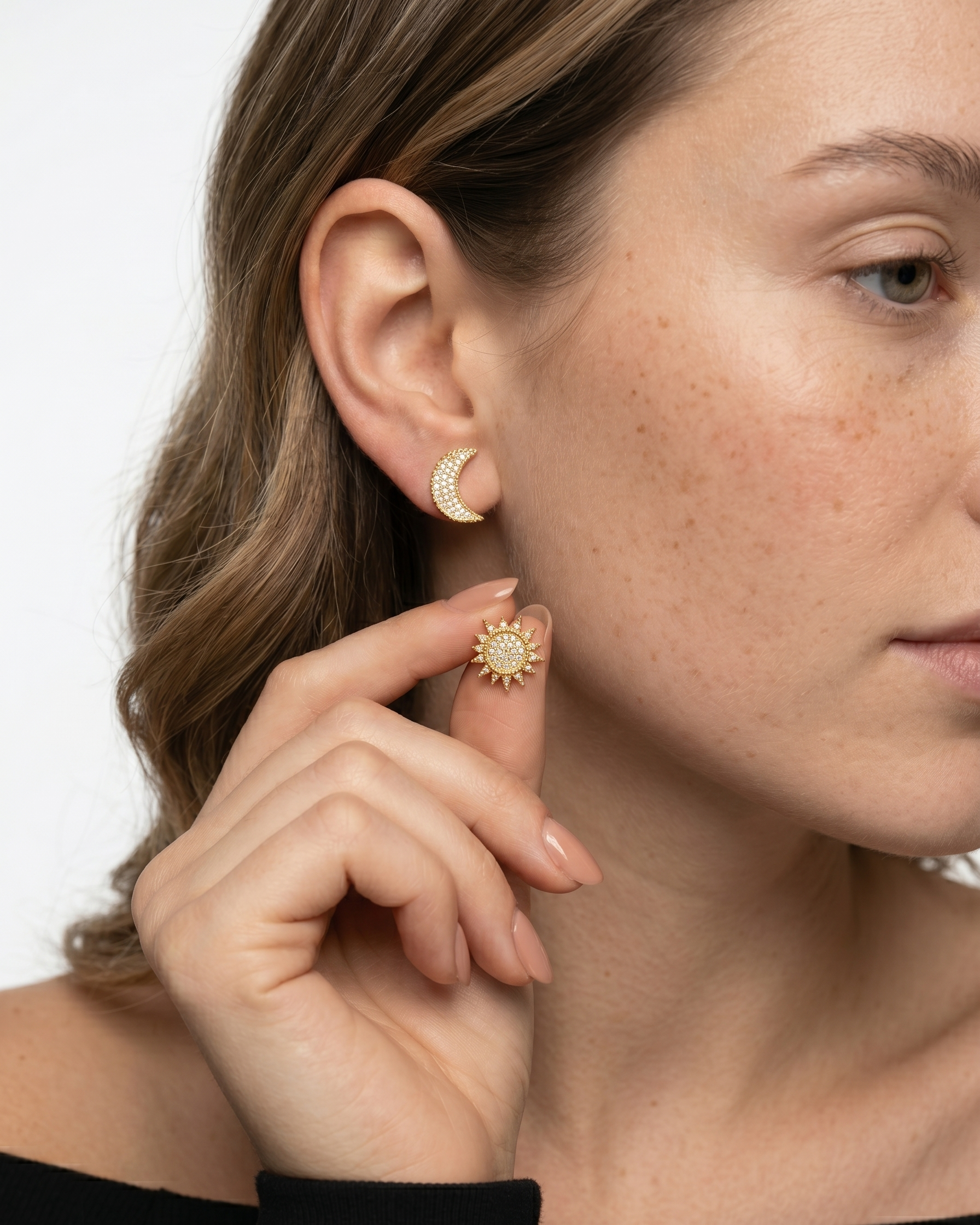 Close-up of a woman wearing gold hoop earrings with a plain background