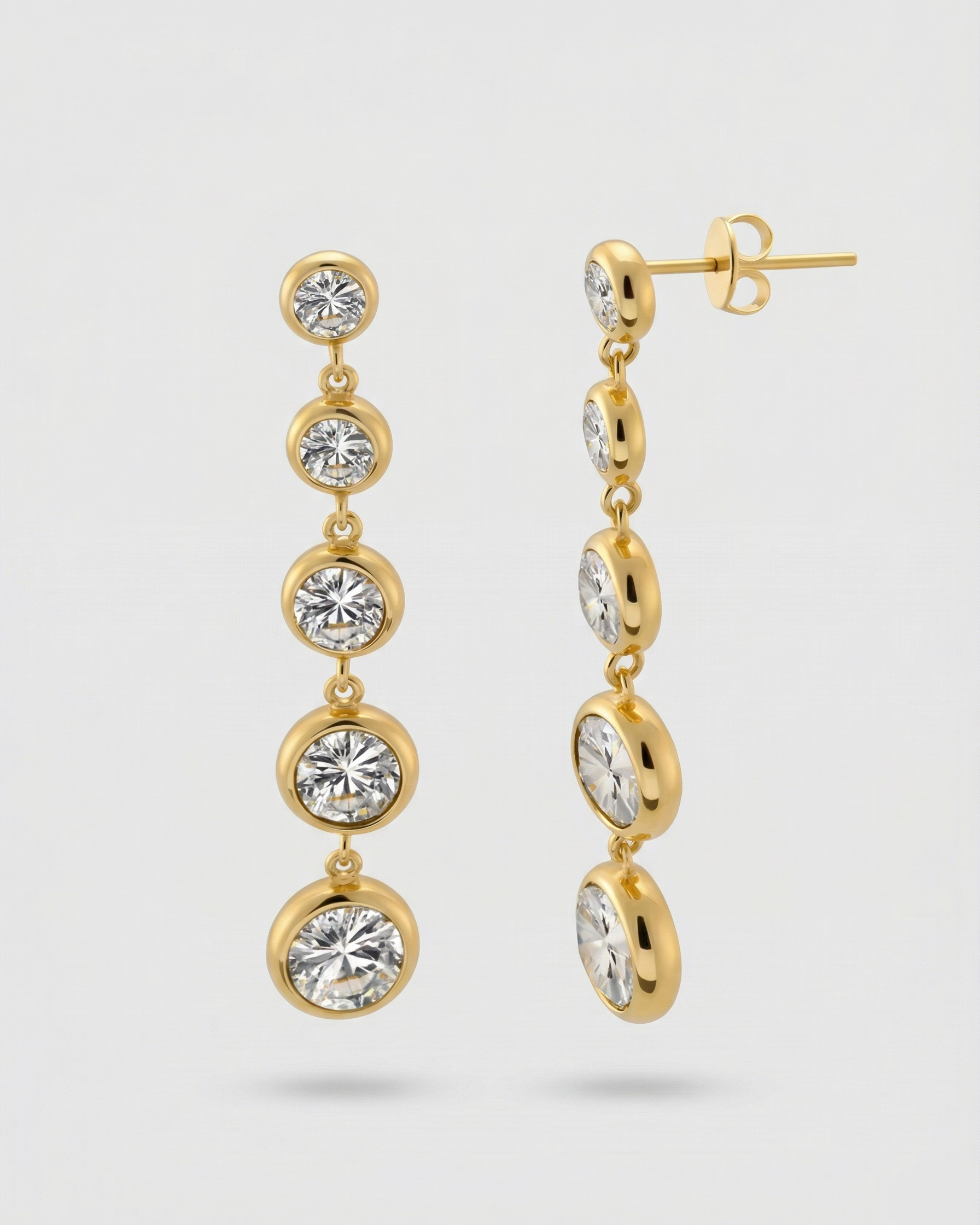 Gold earrings with multiple gemstones on a light gray background